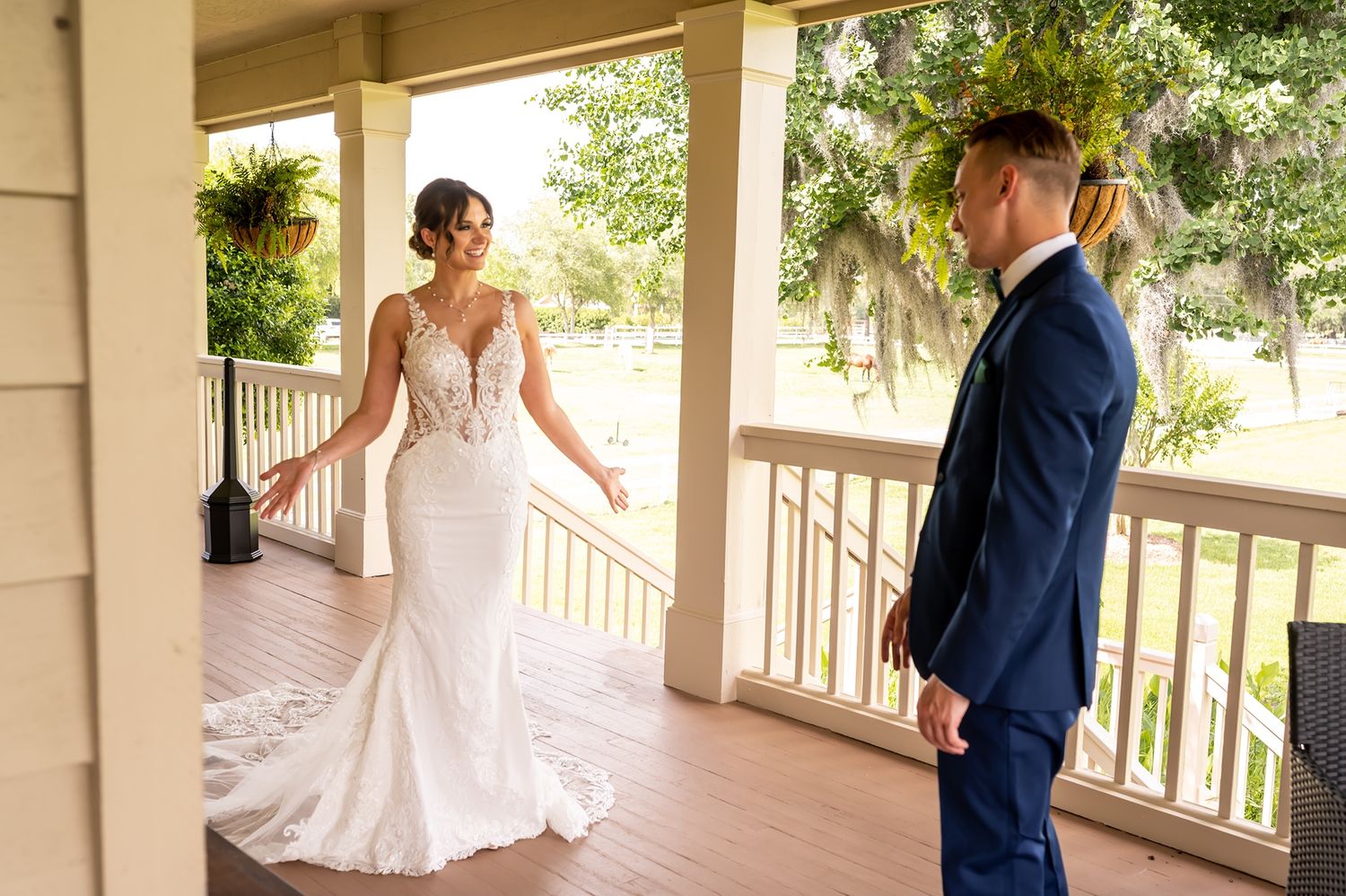A couple sharing their first look moment on a sunlit wraparound porch of a southern estate.