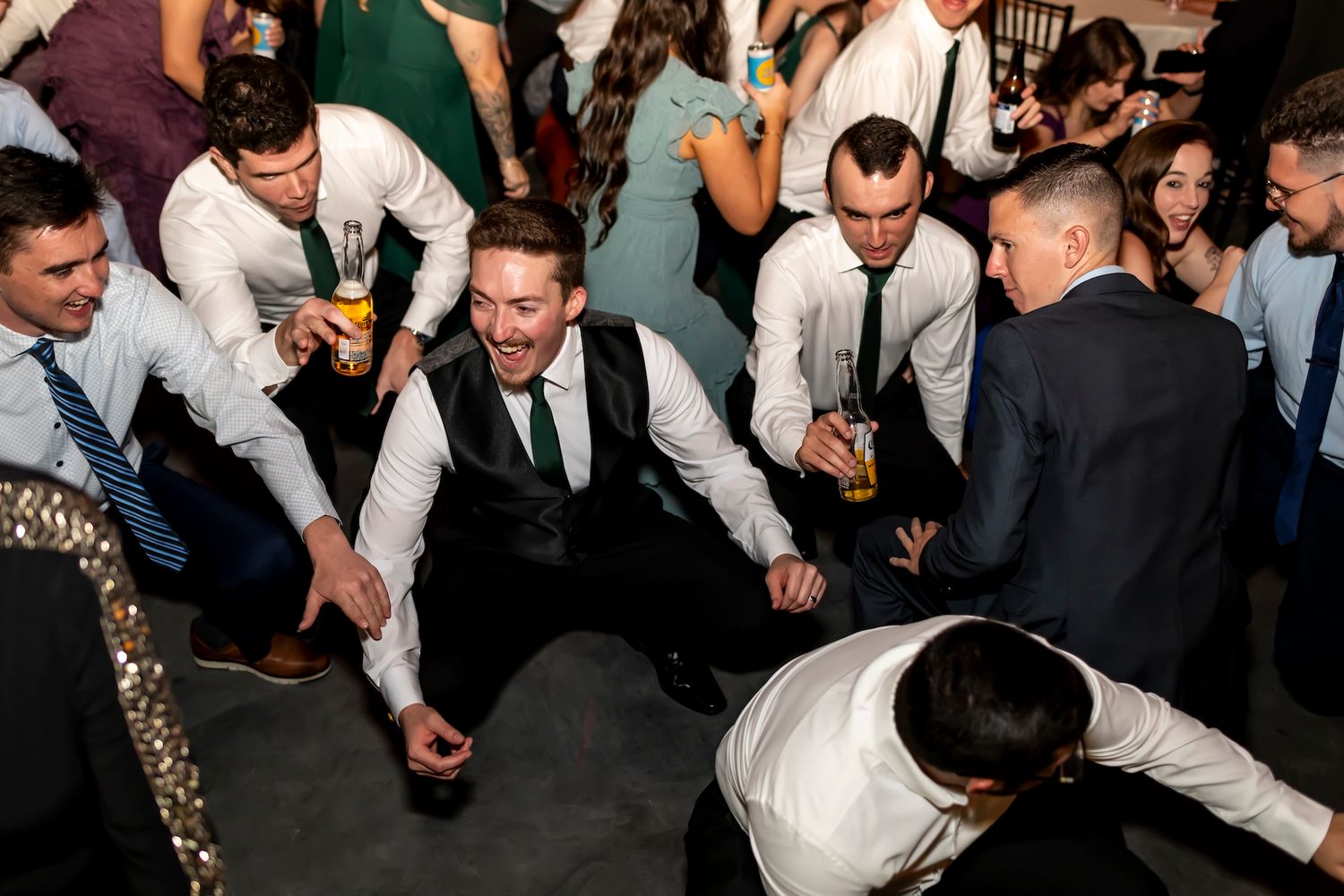Party guests gather around for a lively dance circle at a wedding reception celebration on the dance floor.