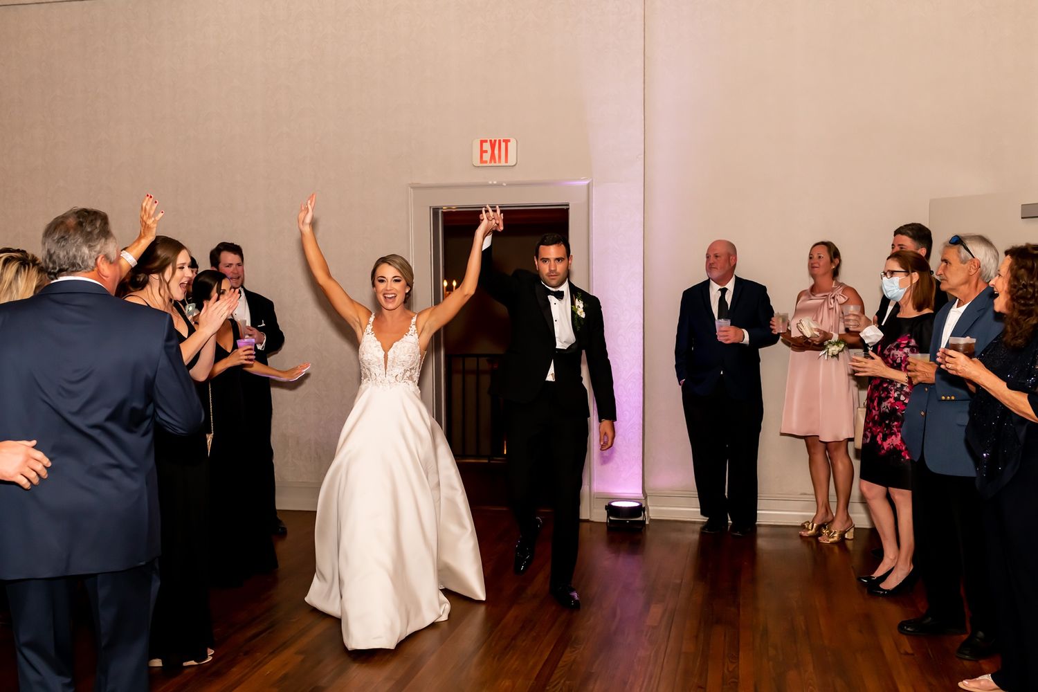 A group of wedding guests dance together on a dance floor at a celebration venue, creating a festive atmosphere.