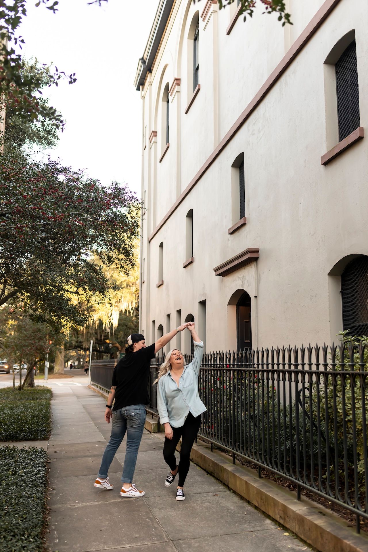 Two people stroll together along a scenic sidewalk beside a grand white historic building.