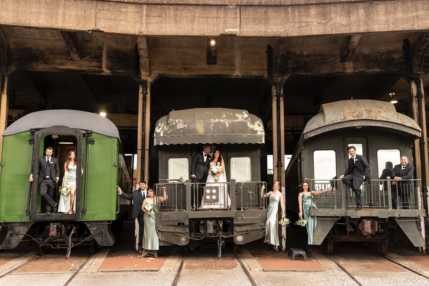 Row of vintage railway cars in an industrial train depot with curved concrete ceiling and natural lighting.