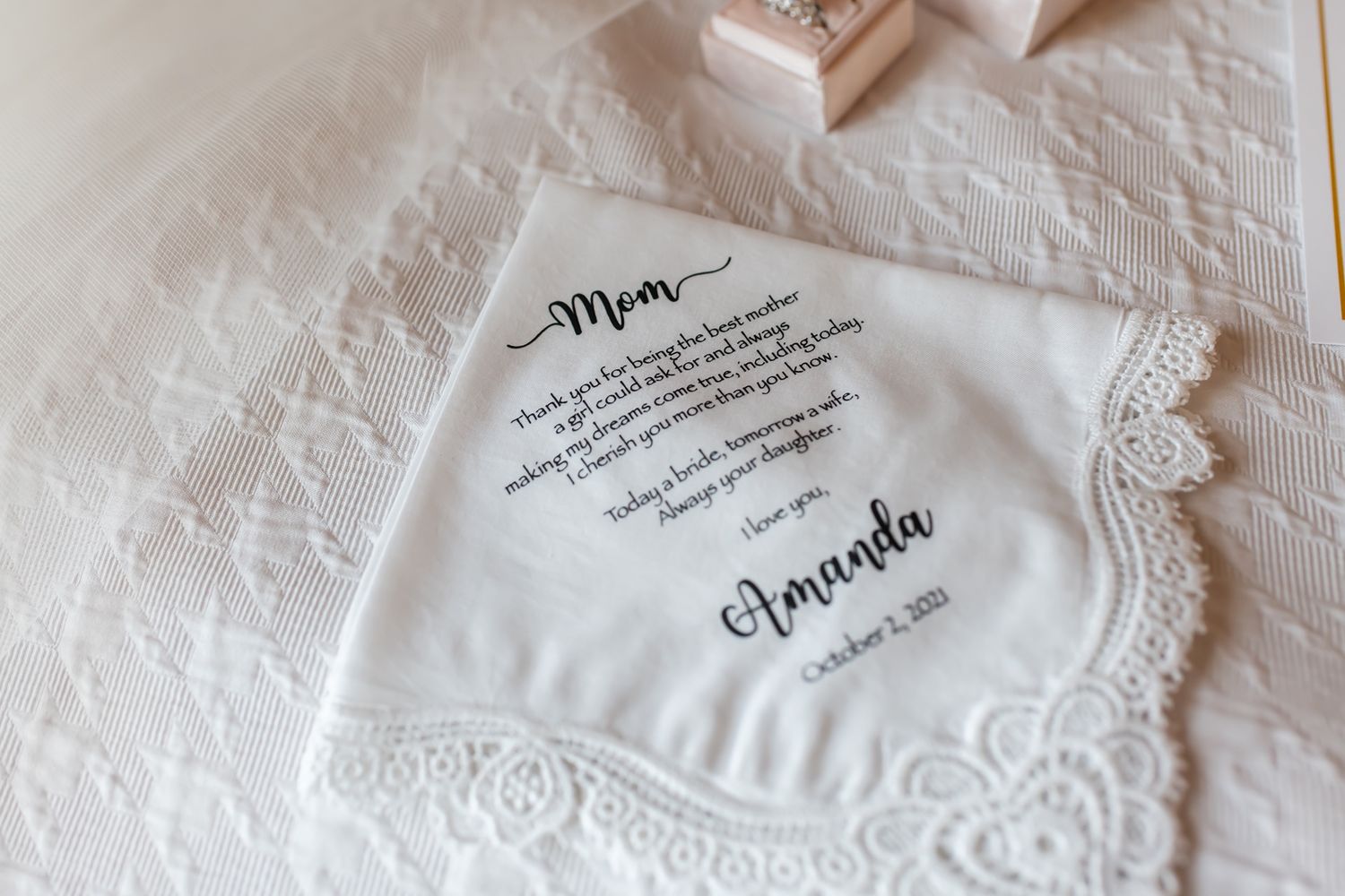 White embroidered handkerchief with delicate lace detail laid flat on textured surface.