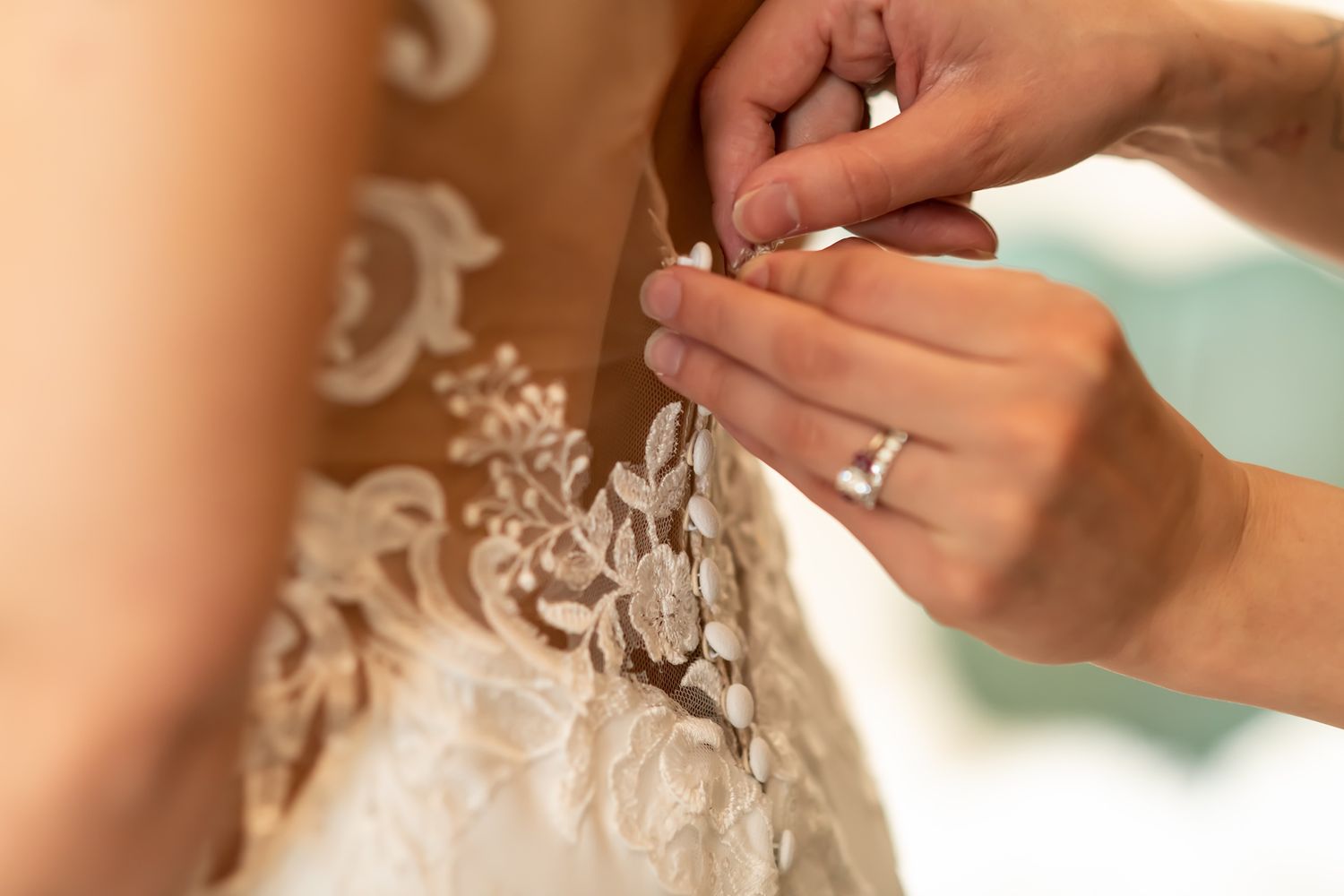 Two hands exchange a silver wedding ring during a ceremony at golden hour.