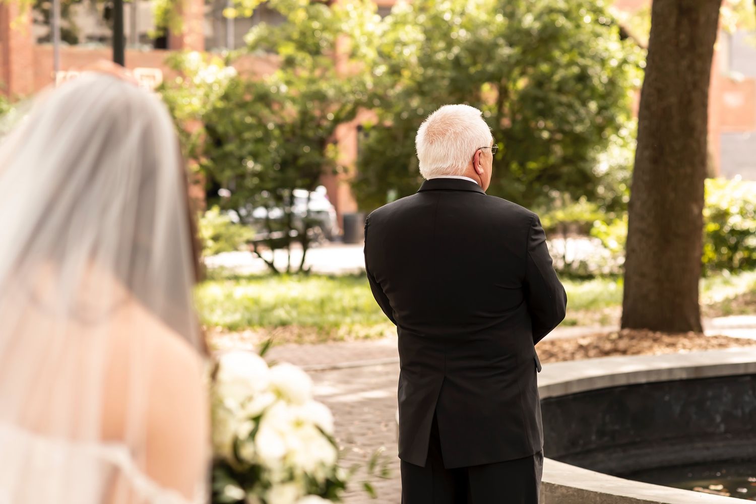 A bride approaches during a wedding ceremony first look moment in an outdoor garden setting.