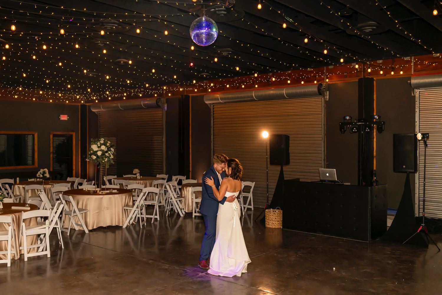 An empty wedding reception venue with twinkling lights strung across the ceiling.