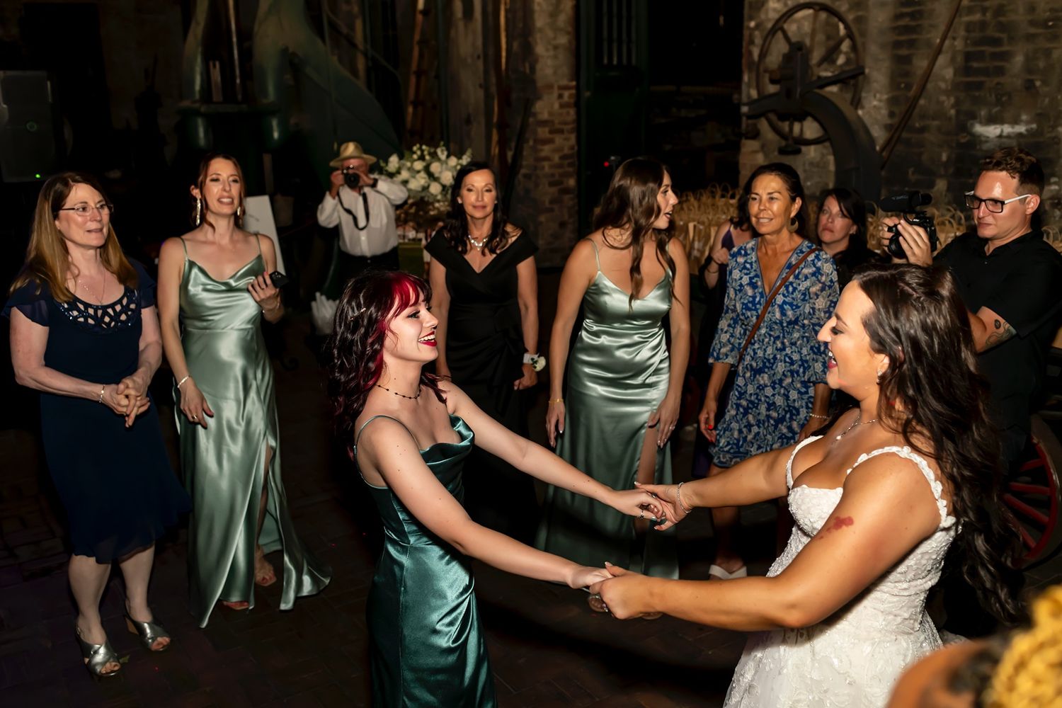 Wedding party dances and celebrates together on a dark dance floor during evening reception party.