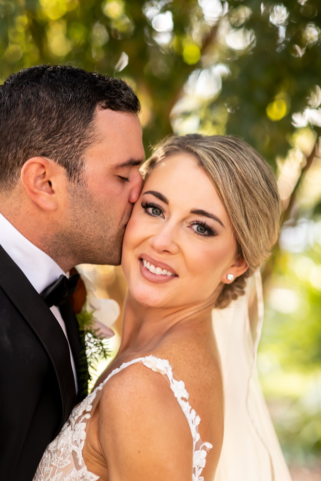 Wedding couple poses for intimate portrait series under natural lighting with white veil details.
