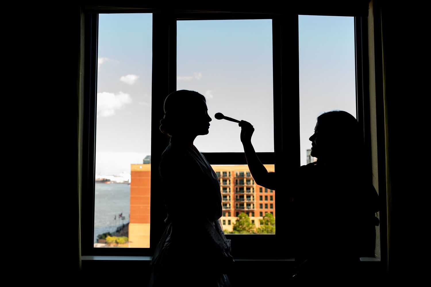 A sequence of silhouetted figures against bright windows showing an urban skyline in the background.