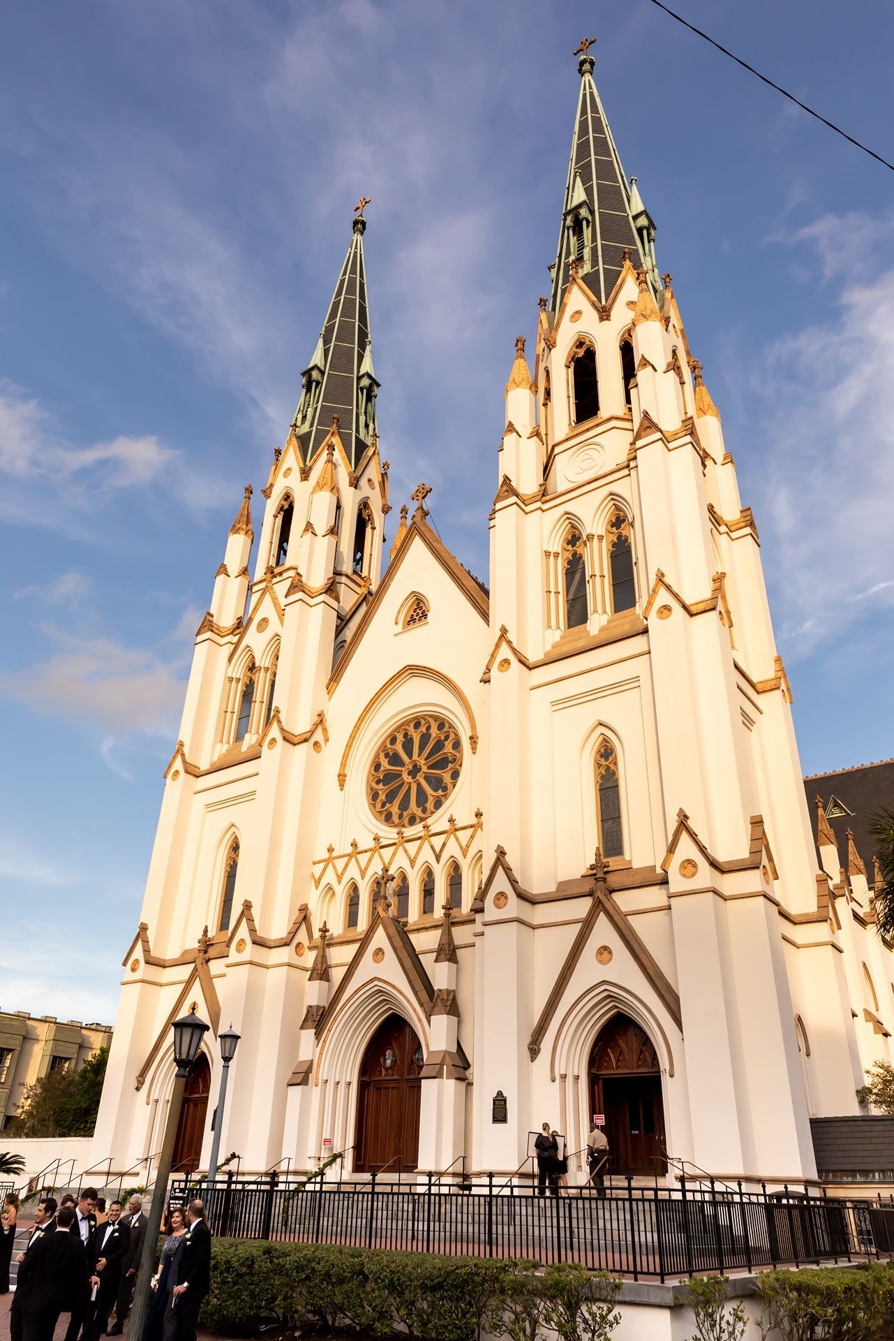 Gothic revival architecture of St. John the Baptist Cathedral with twin spires against a blue sky in Savannah, Georgia.