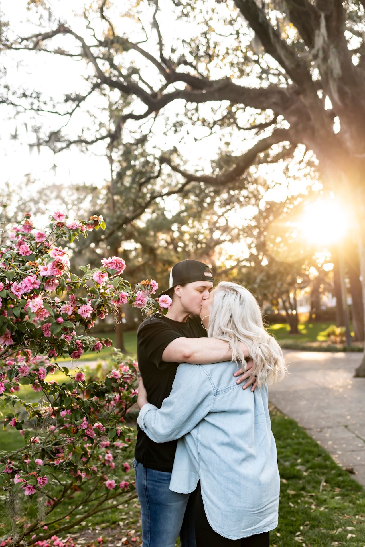 A romantic moment shared between two people near blooming pink flowers at sunset.