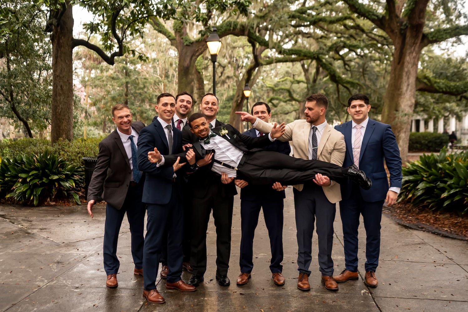 Wedding party shows off their colorful socks in a playful group photo outdoors.