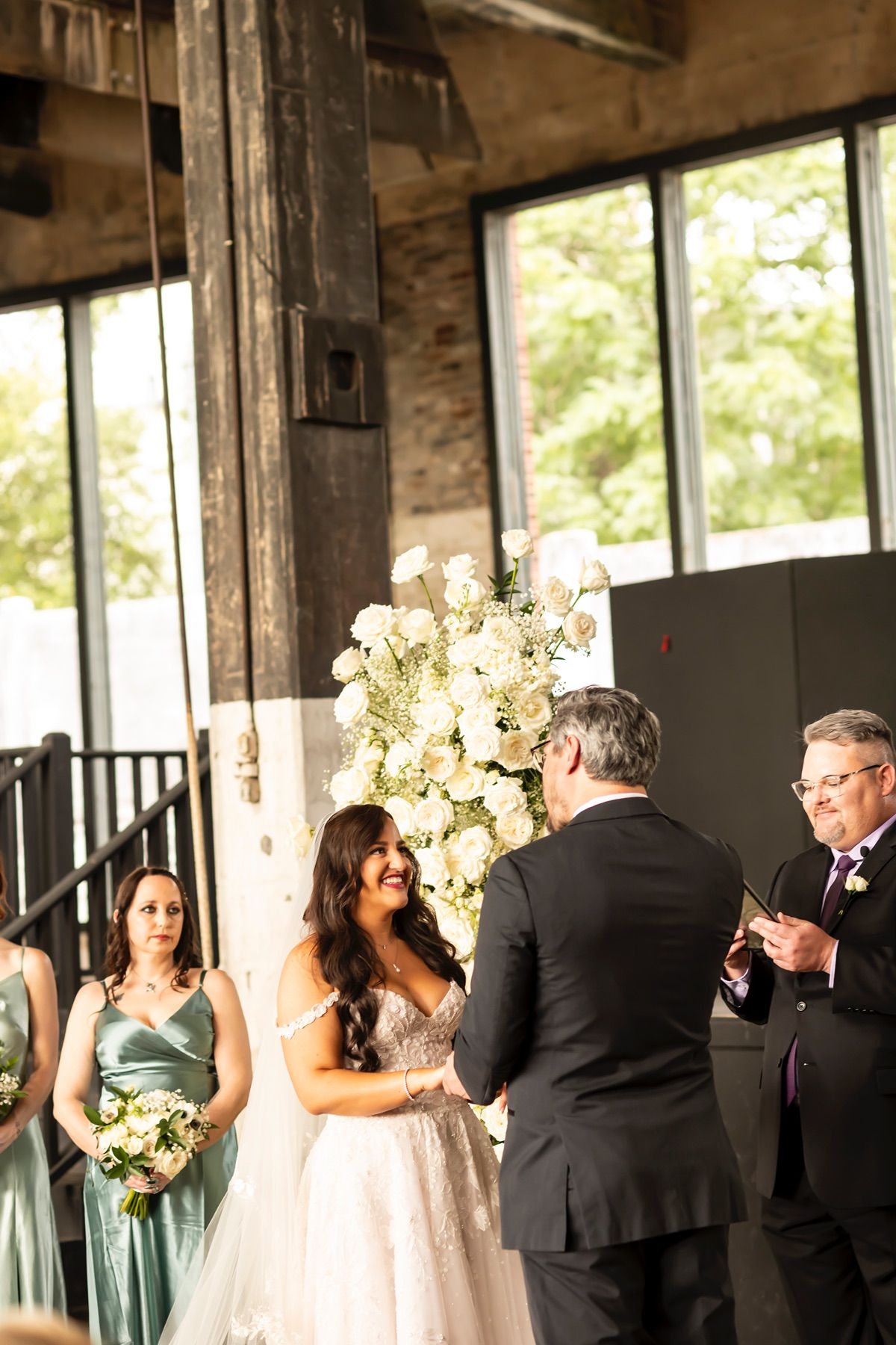 Indoor wedding ceremony venue with tall windows, wooden beams, and a large floral arrangement creating a romantic atmosphere.