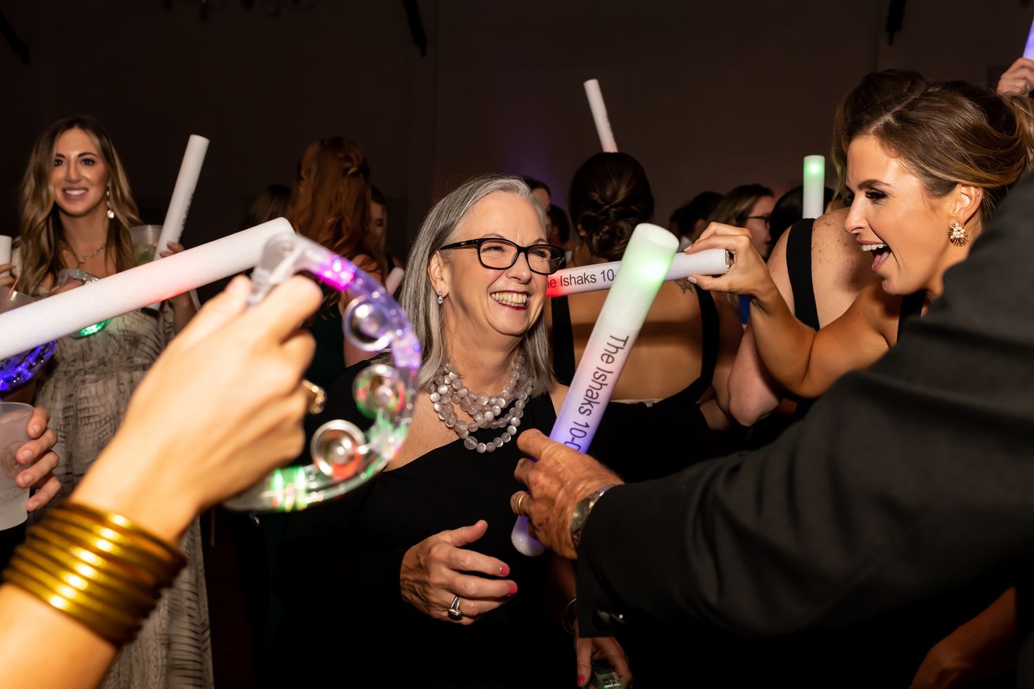 A dimly lit party scene with people holding illuminated personal devices.