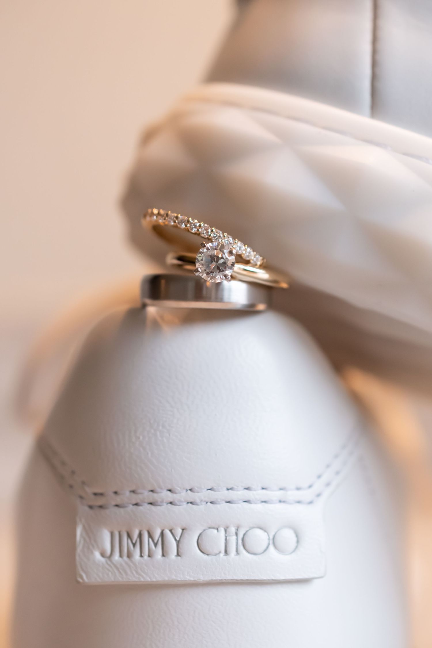 Wedding rings balanced on a white Jimmy Choo shoe showing intricate wedding rings.