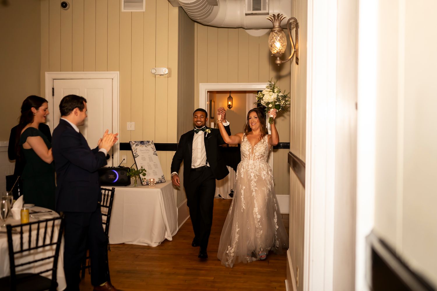 Guests applaud as a couple makes their grand entrance into an elegantly decorated reception venue.