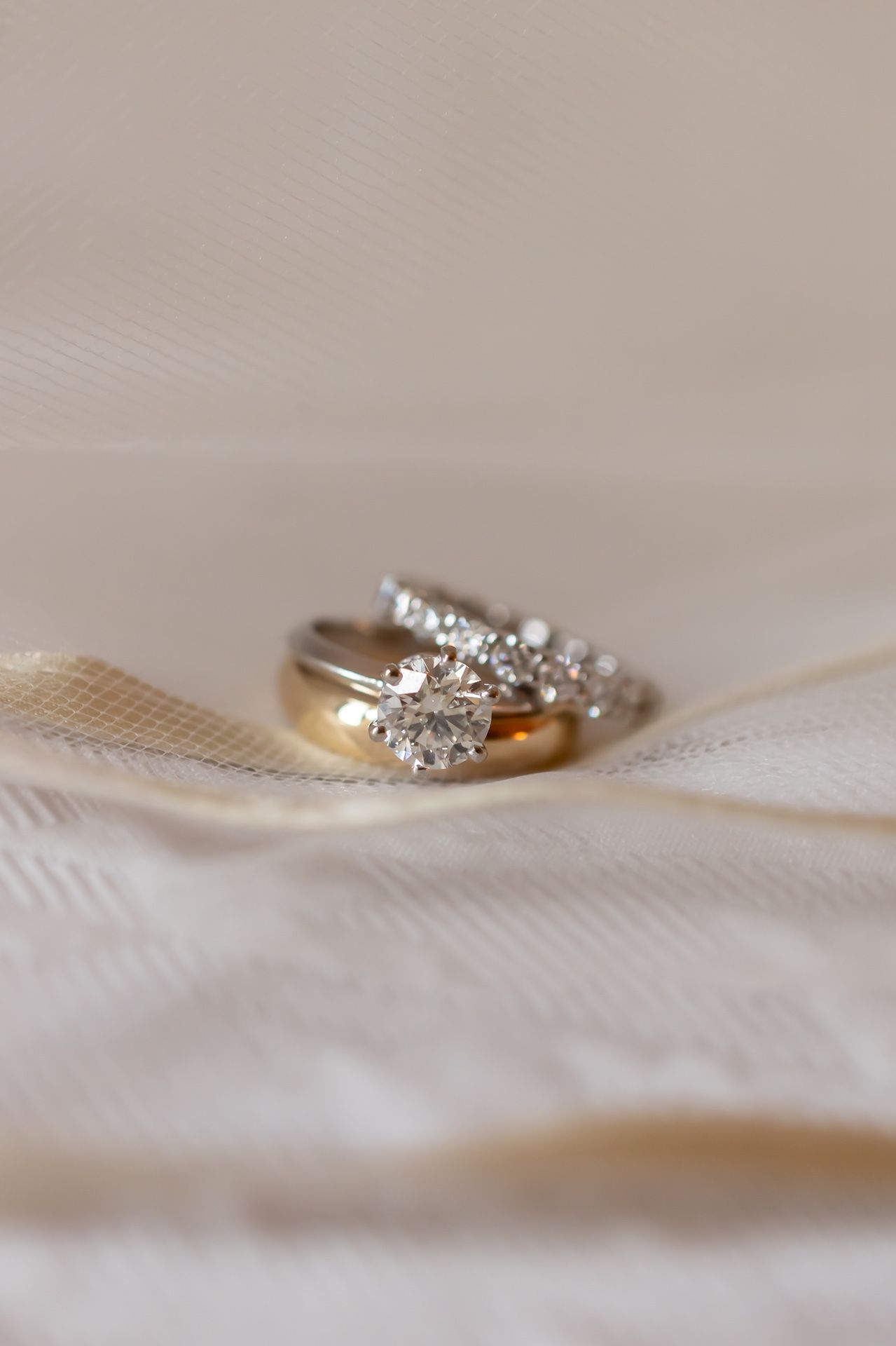 Close-up sequence of a delicate diamond wedding ring on white fabric, shown from different angles and depths of field.