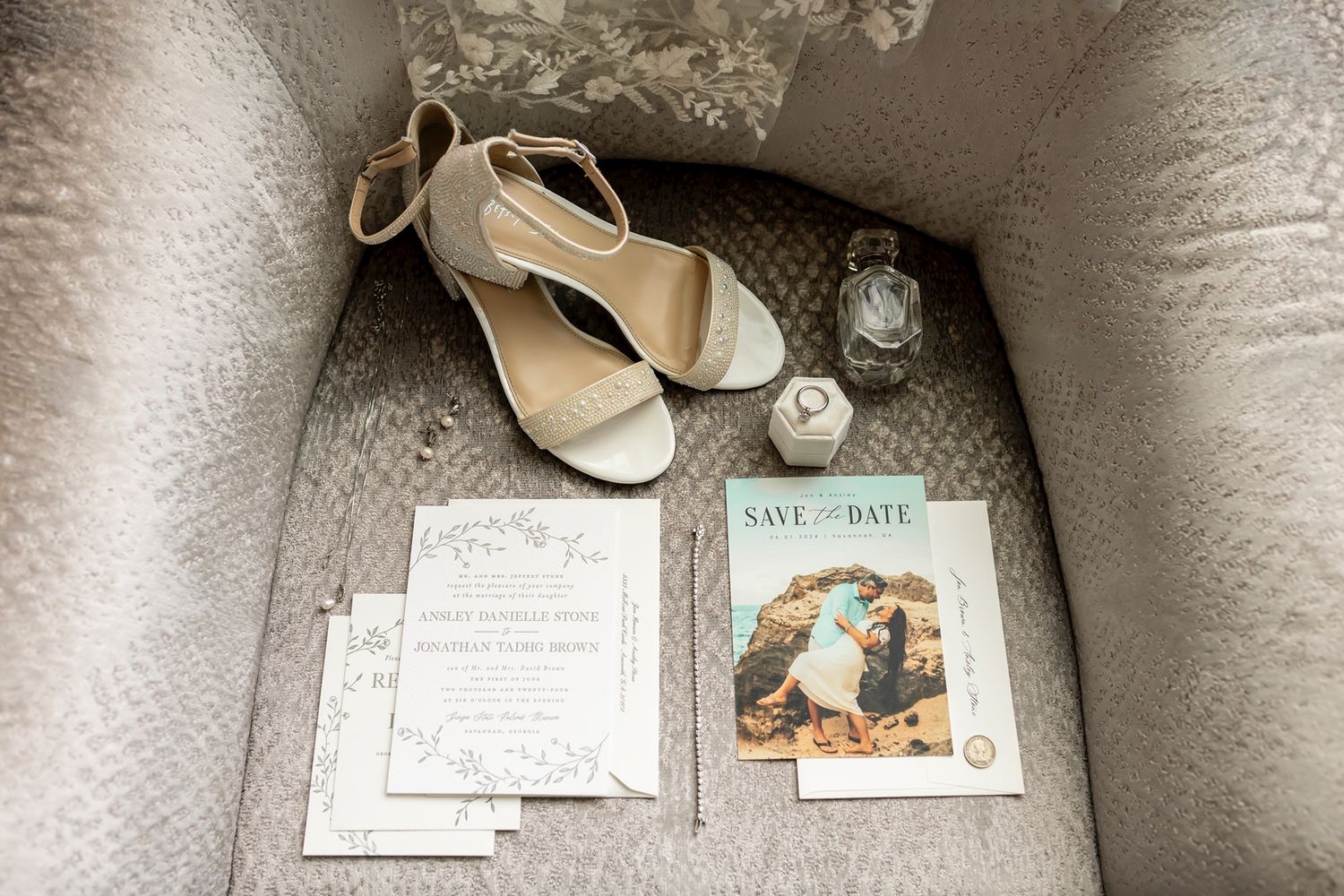 Wedding invitation suite displayed on textured surface with elegant calligraphy and multiple layered cards in neutral tones.