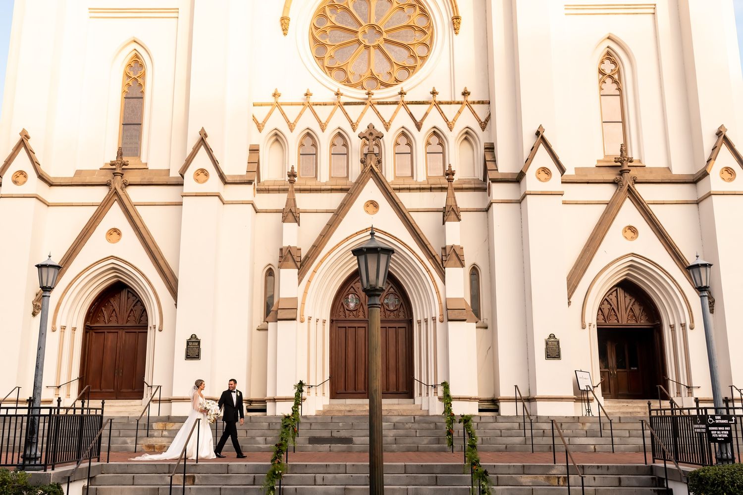 Exterior view of ornate white church facade with multiple arched doorways and Gothic architectural details.