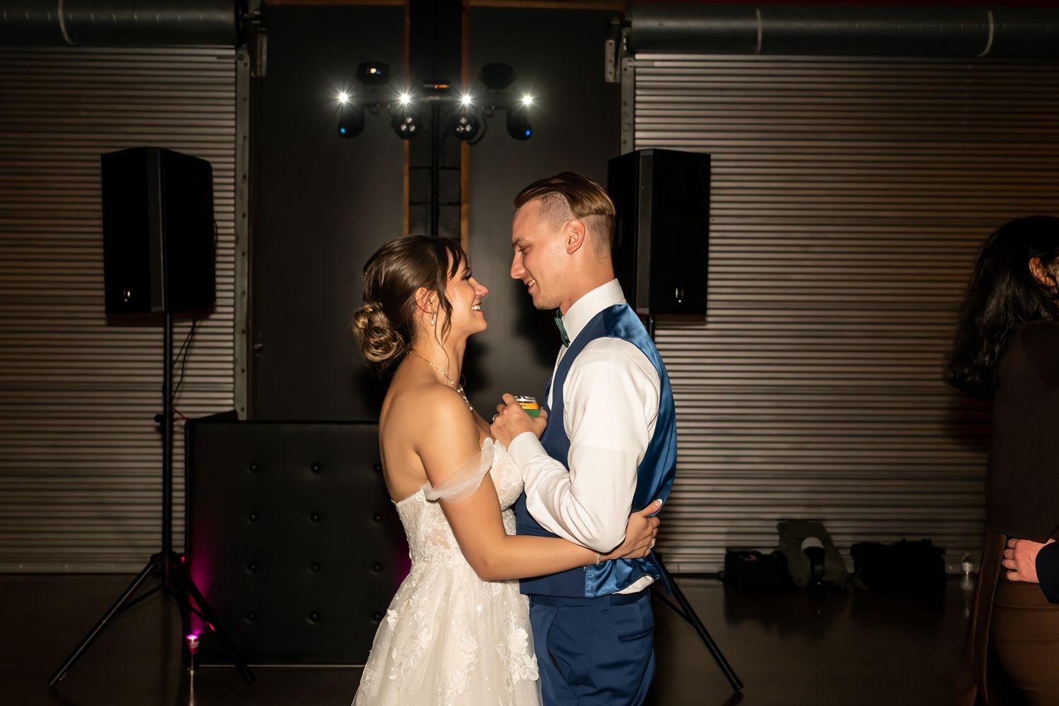 Romantic couple dances in a dimly lit venue during their first dance at the wedding reception.