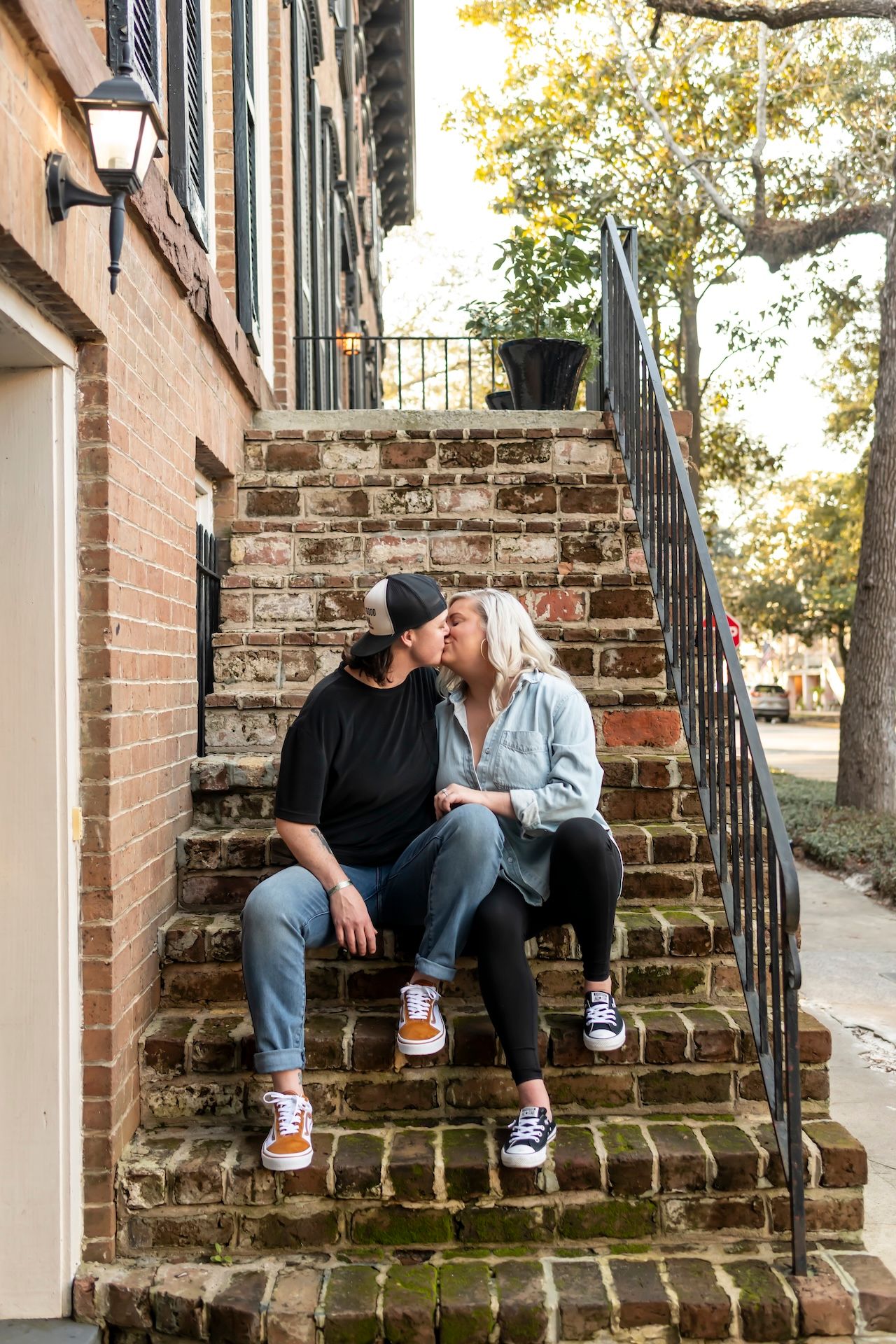 Couple wearing matching sneakers sitting together on vintage brick steps of a historic building.