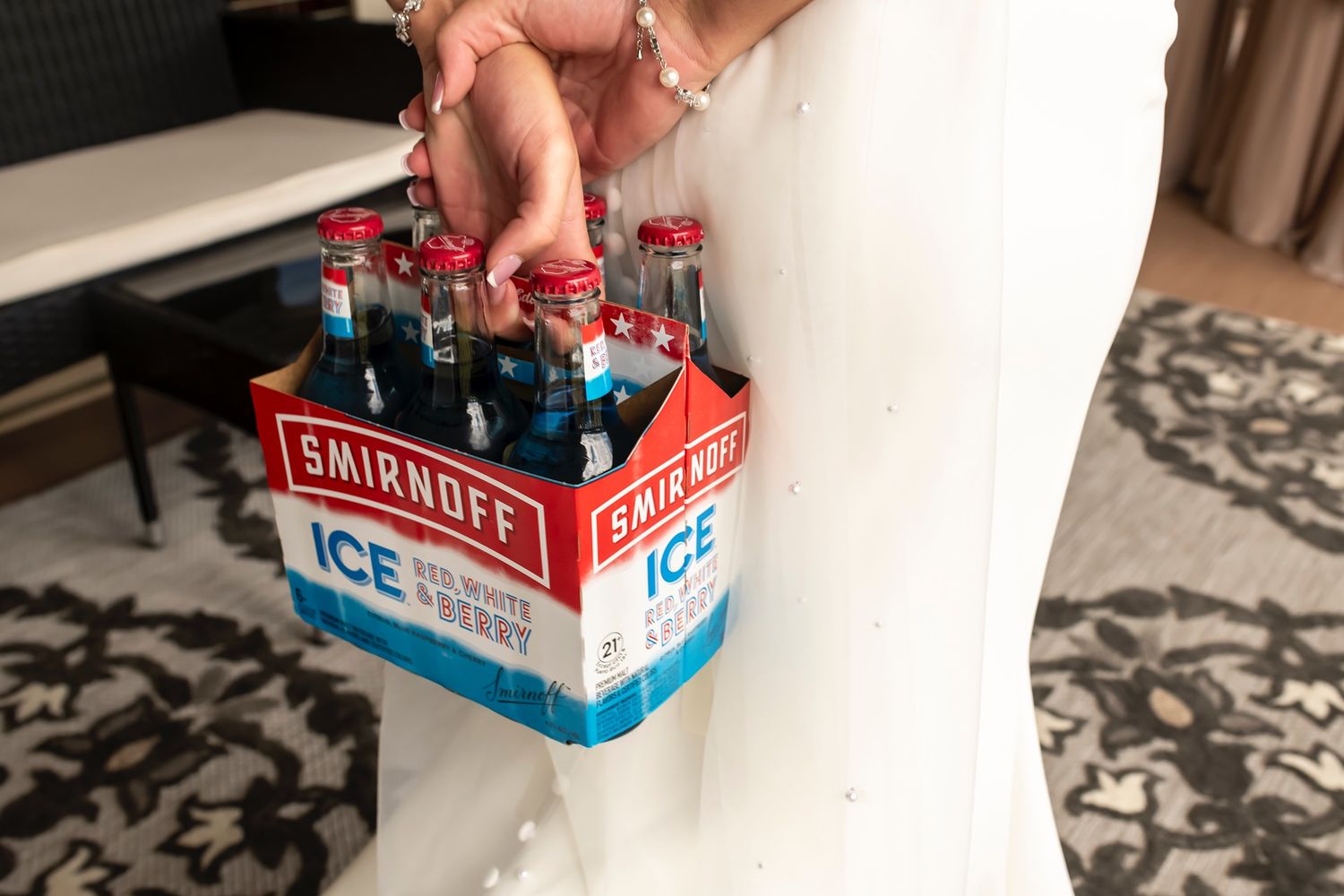 Hands remove bottles from vintage style Coca-Cola carriers showing staggered steps of the removal process.