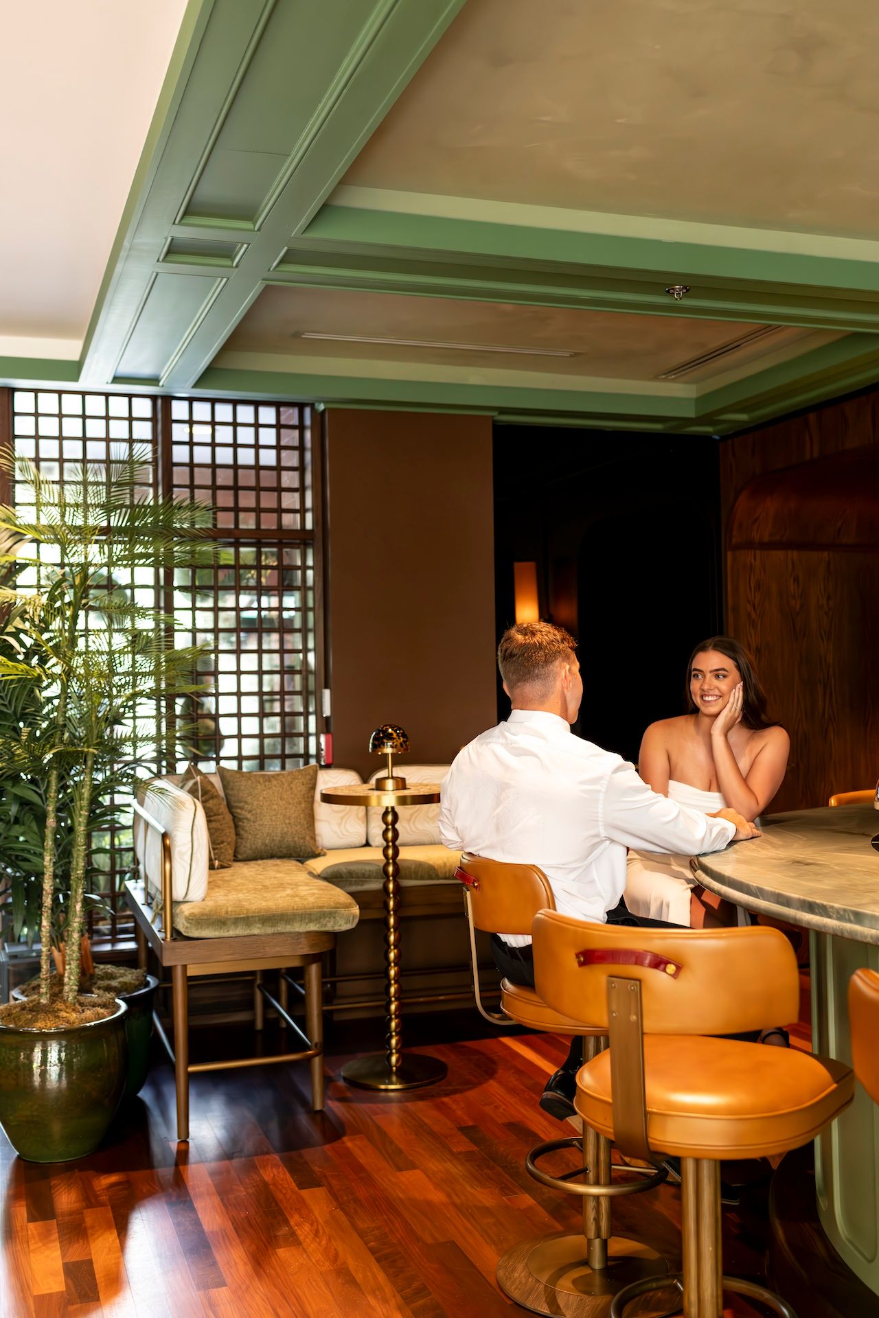 Friends enjoying conversation while relaxing on lounge chairs in a cozy room with hardwood floors and warm lighting.