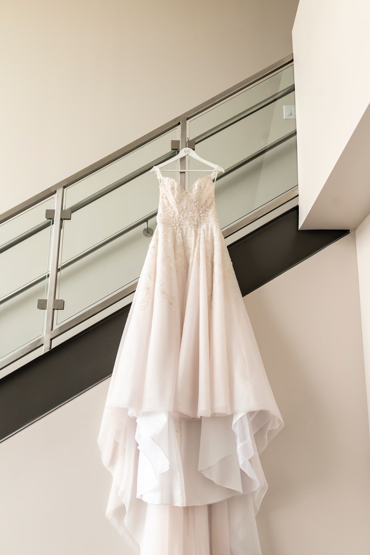 White flowing wedding dress details shown in a series of close-up images hanging against a modern interior wall.