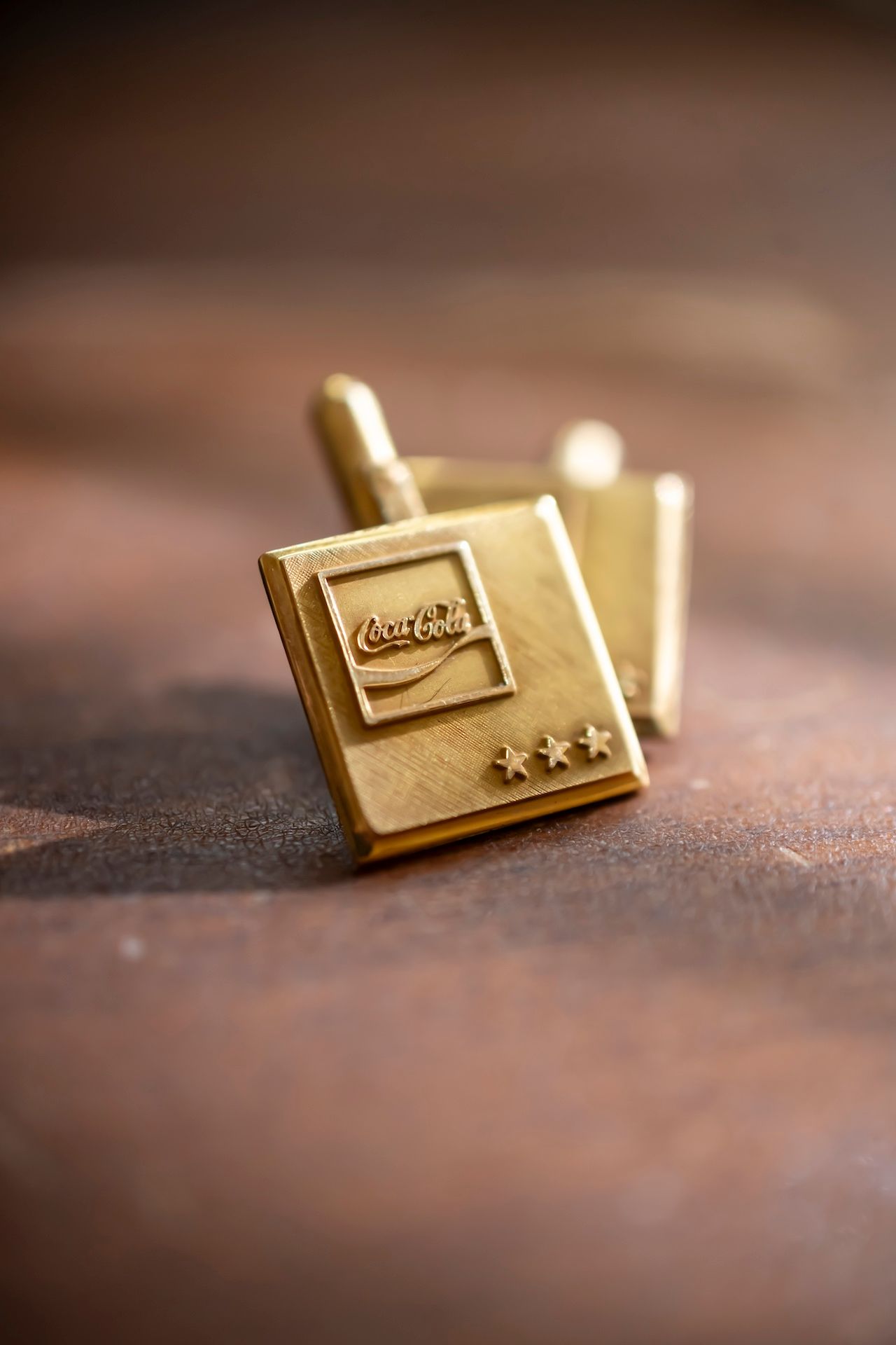 Gold plated Nike swoosh lapel pin photographed from multiple angles on a textured brown leather surface in macro detail.