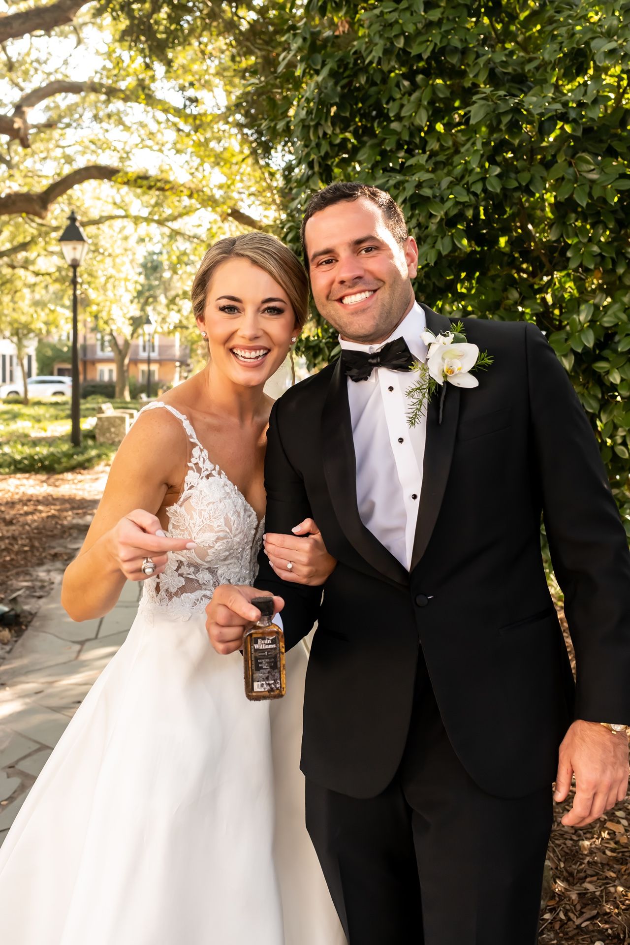A newlywed couple sharing a joyful moment outdoors on their wedding day with natural lighting and greenery in the background.
