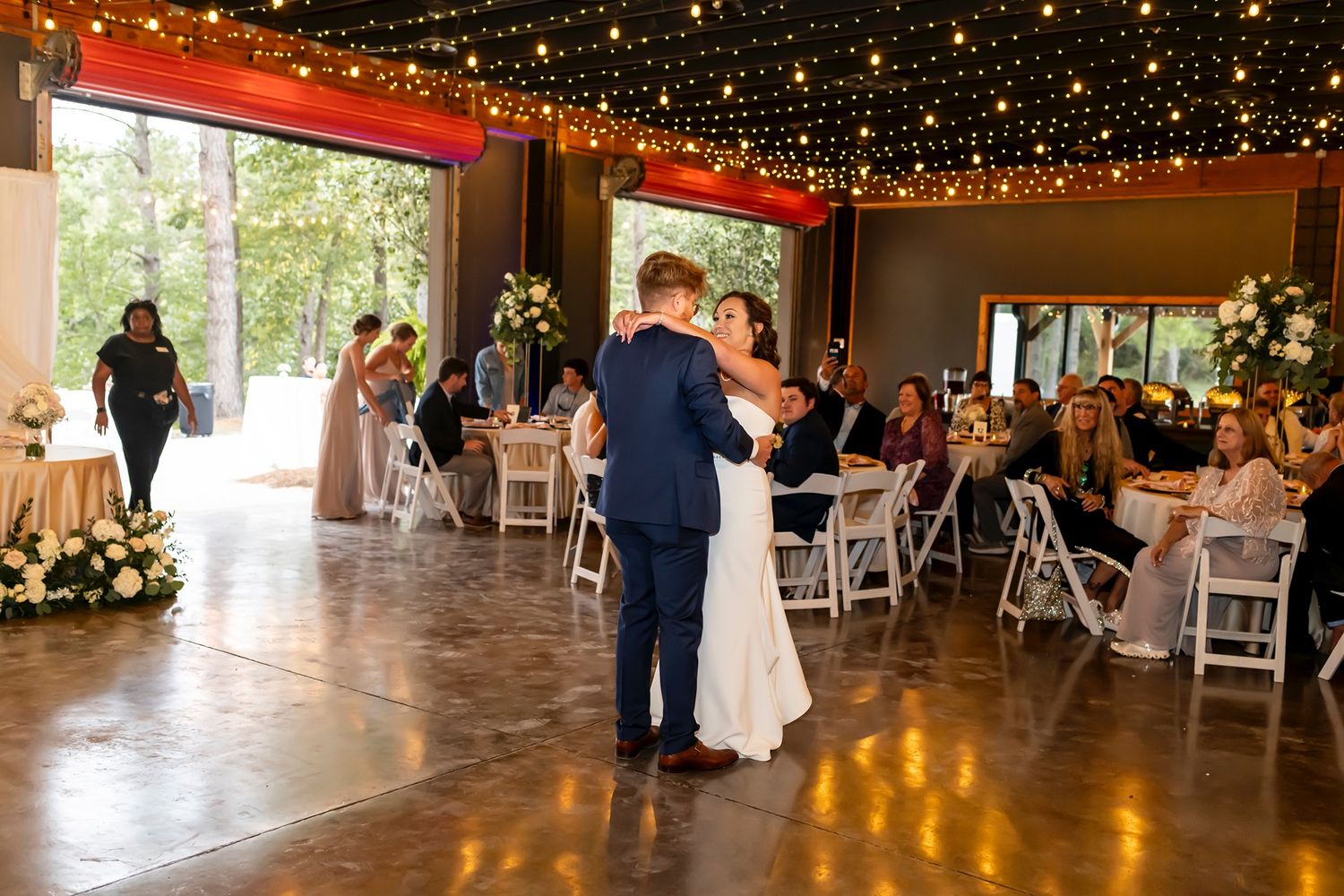 Wedding reception venue decorated with string lights and guests seated at tables for celebration.
