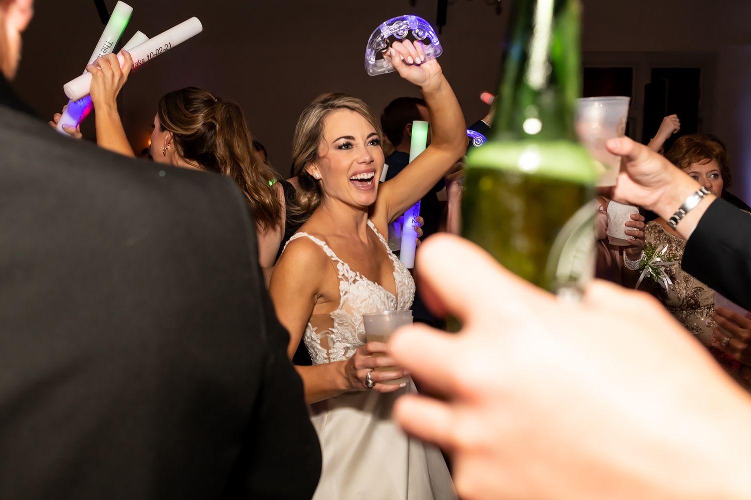 Excited person dancing and celebrating on crowded dance floor at nighttime party with colorful lighting.