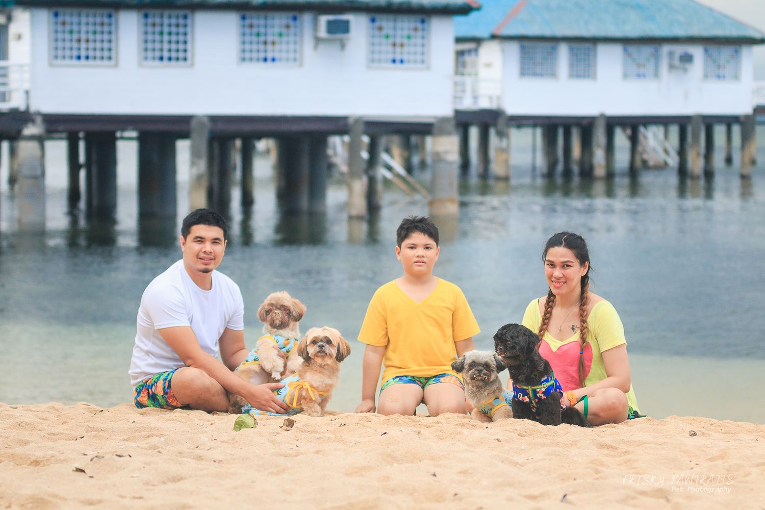 outdoor portrait by the beach of a family with their shih tzu dogs