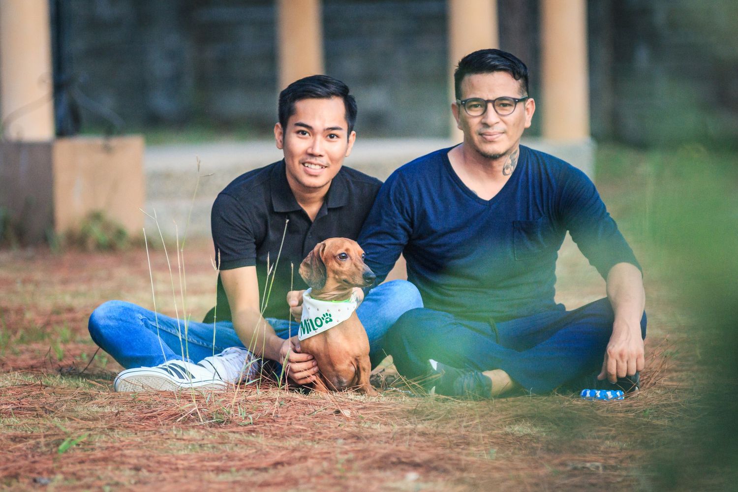Father and son spending quality time outdoors playing with a golden retriever puppy on sunny day.