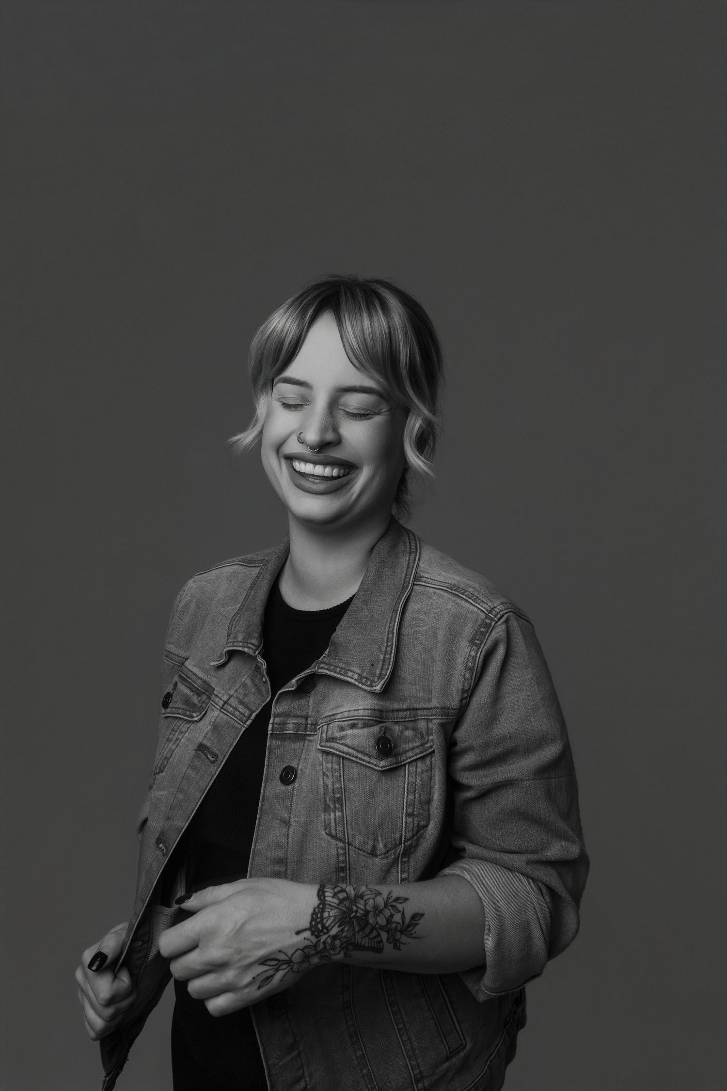 Black and white portrait series showing expressions of joy and laughter while wearing a denim jacket.