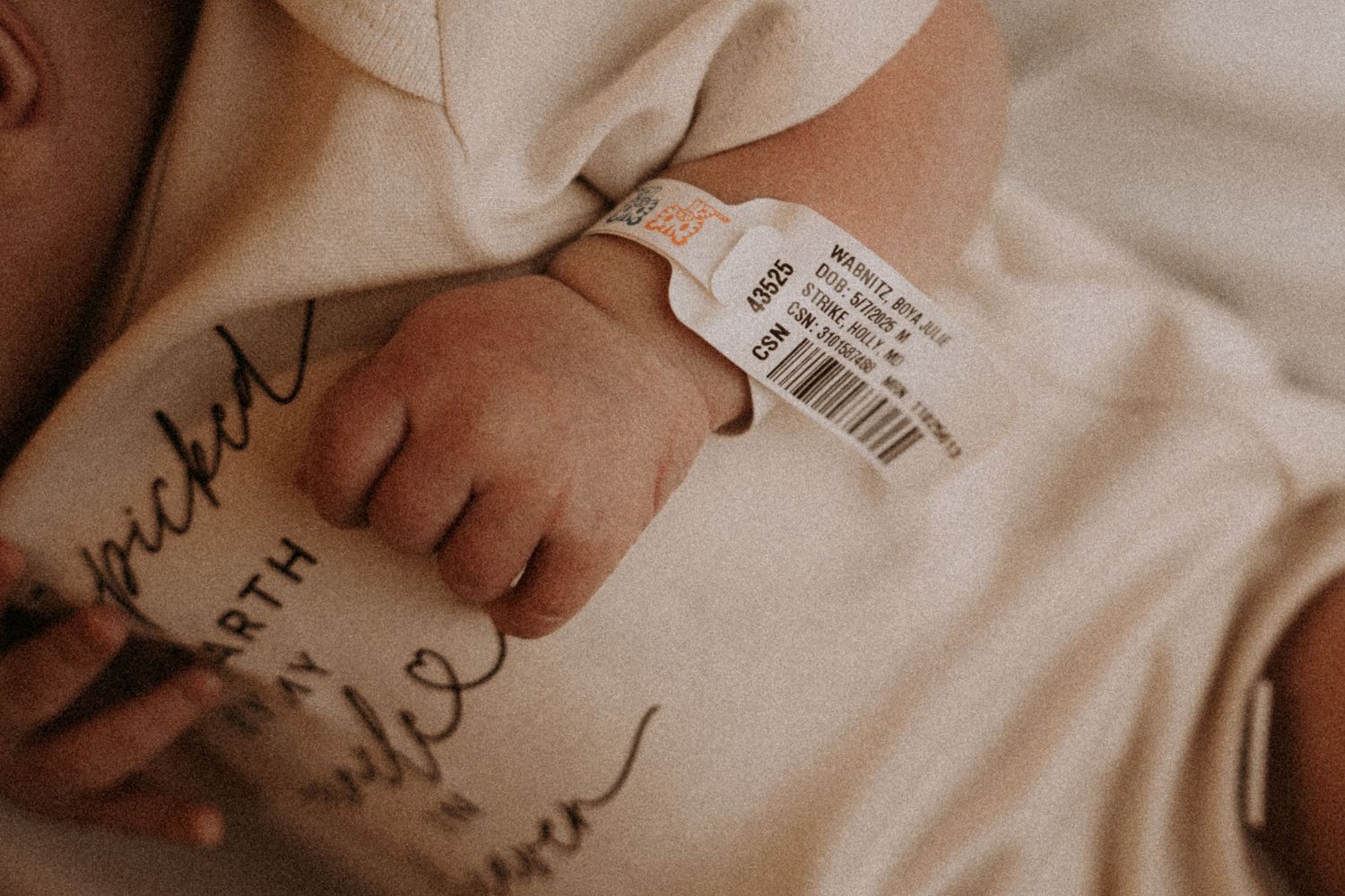 Detail shot of baby's hospital identification tag and clothing in warm tones.