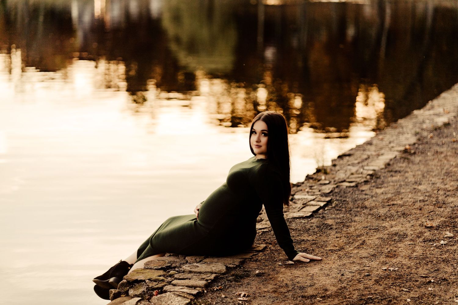 Artistic sunset maternity photo by a reflective lake.