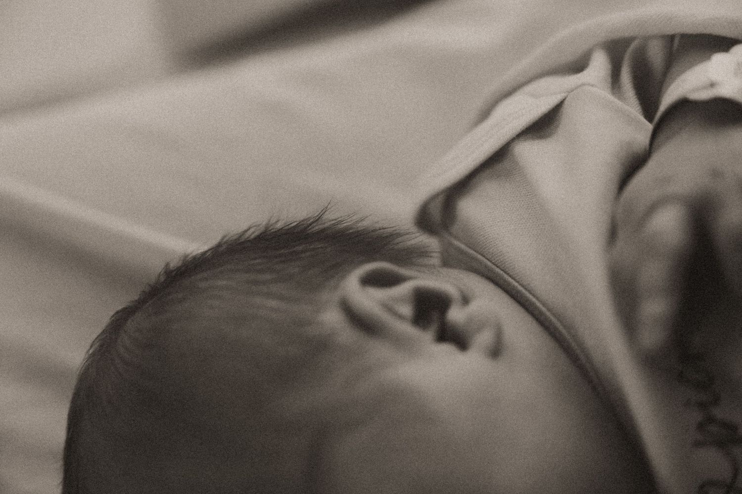 Gentle black and white image of newborn resting in hospital attire.
