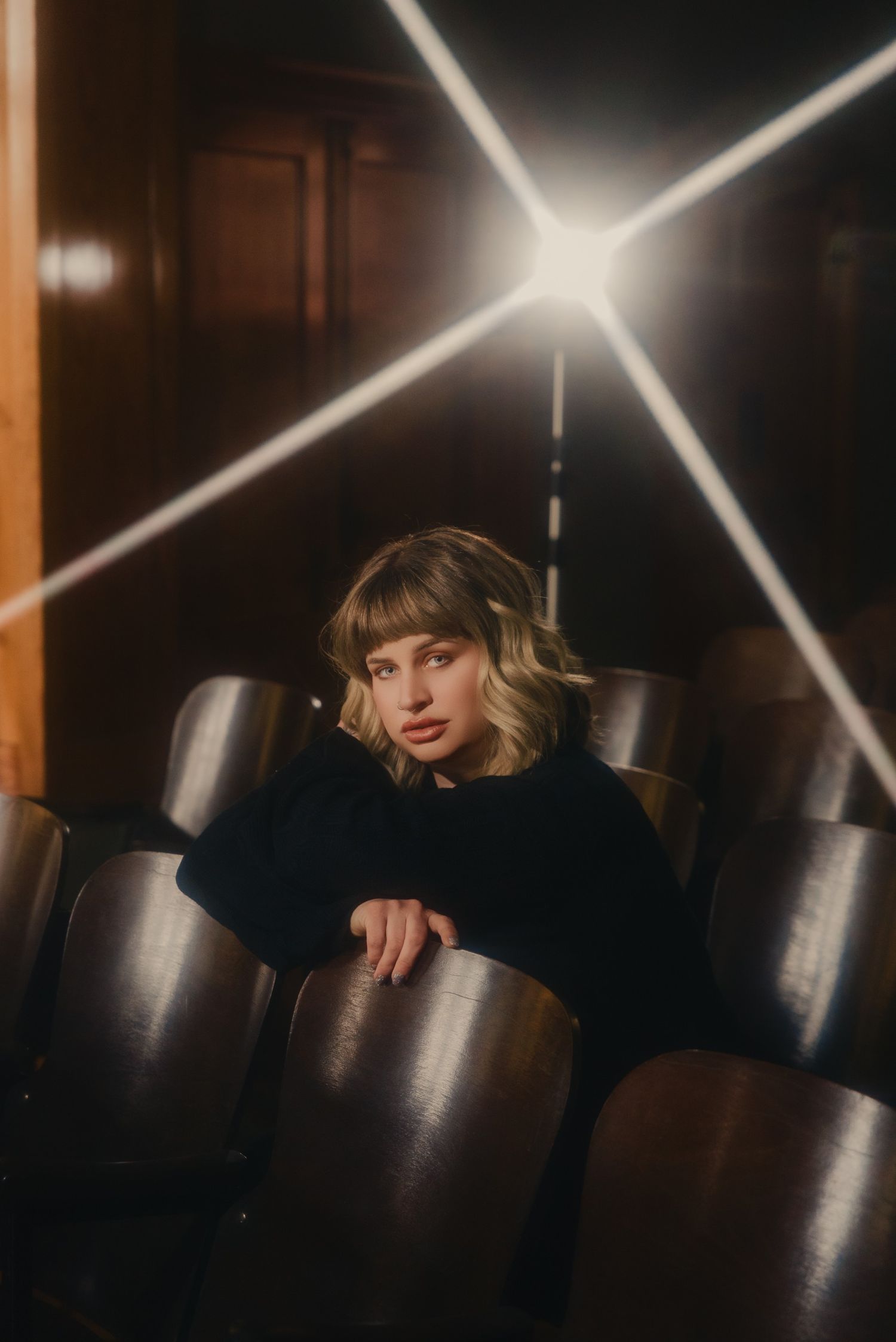 Moody theater portrait with dramatic starburst lighting effect and vintage seating.