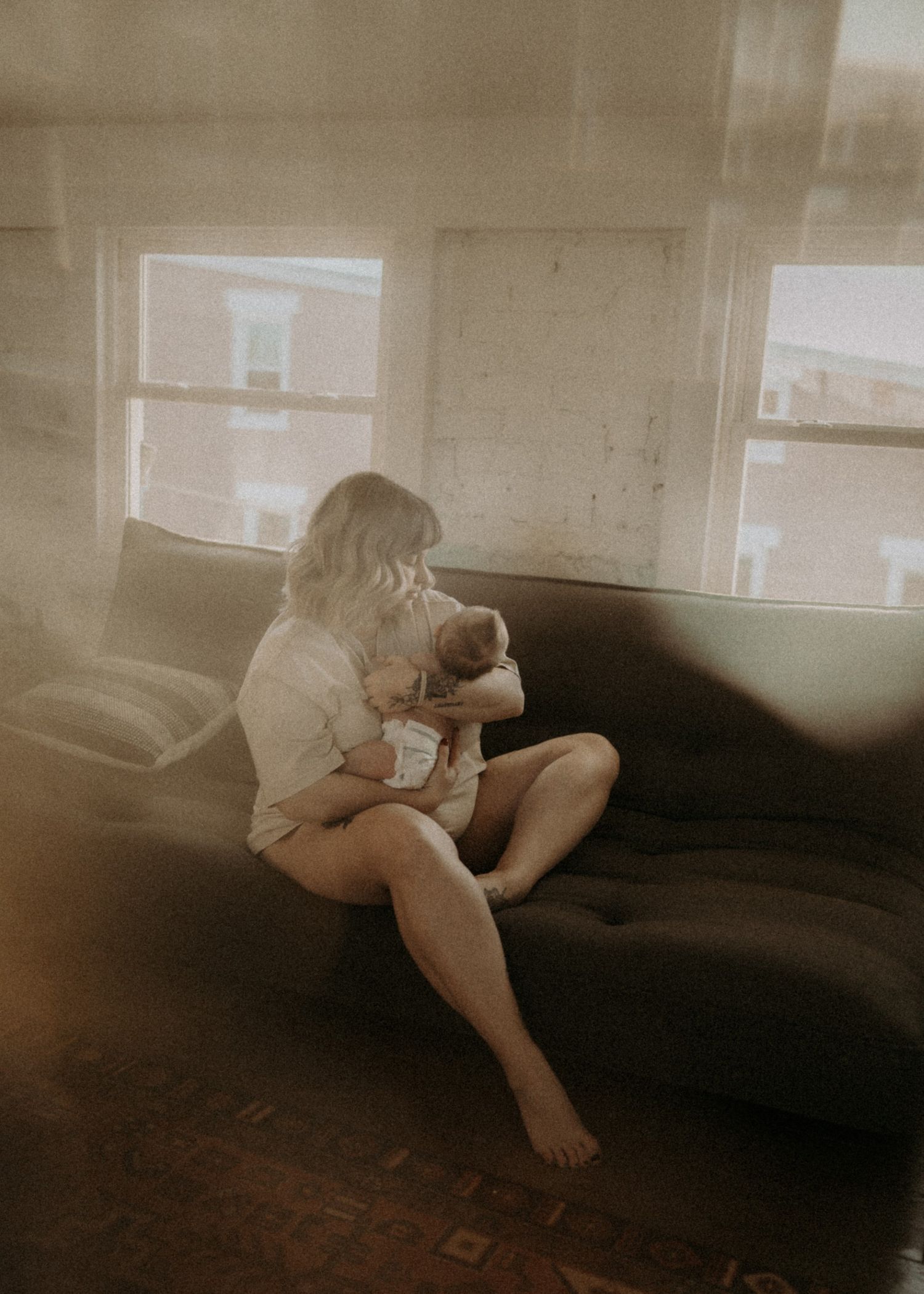 Soft vintage-toned indoor portrait on dark couch near window light.