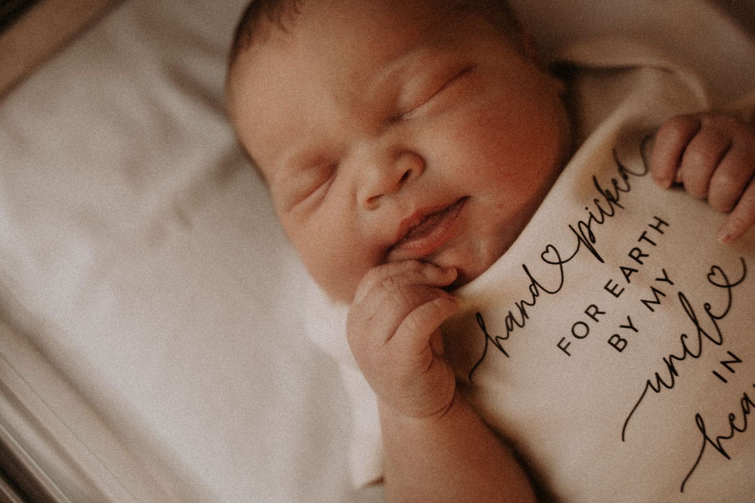 Artistic portrait of sleeping newborn with visible hospital identification details.