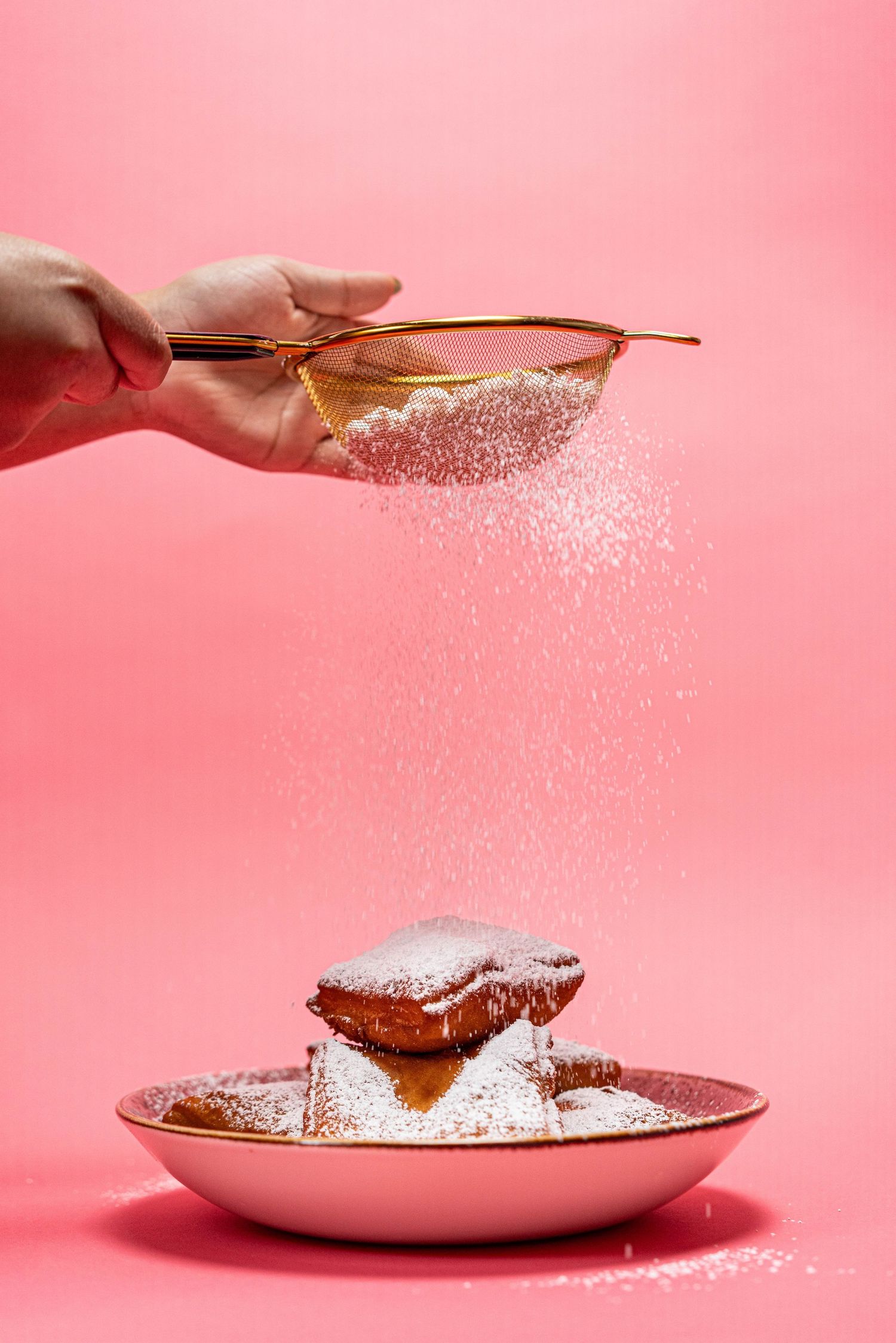 beignets being dusted with powdered sugar