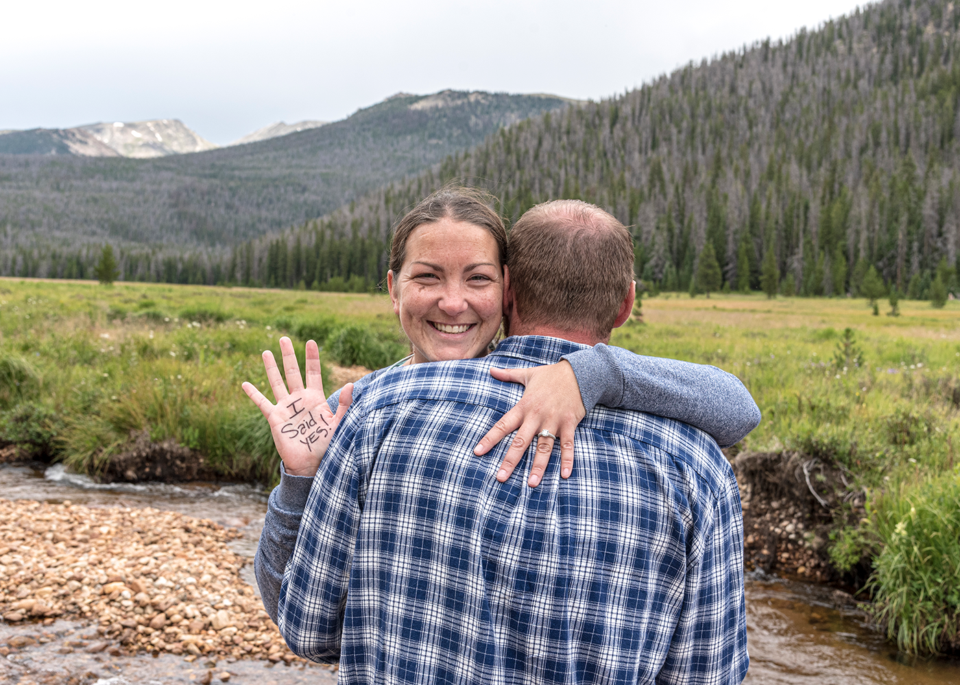 Woman showing off her hands after she said yes to his surprise marriage proposal inside Rocky Mountain National Park at Big Meadow.