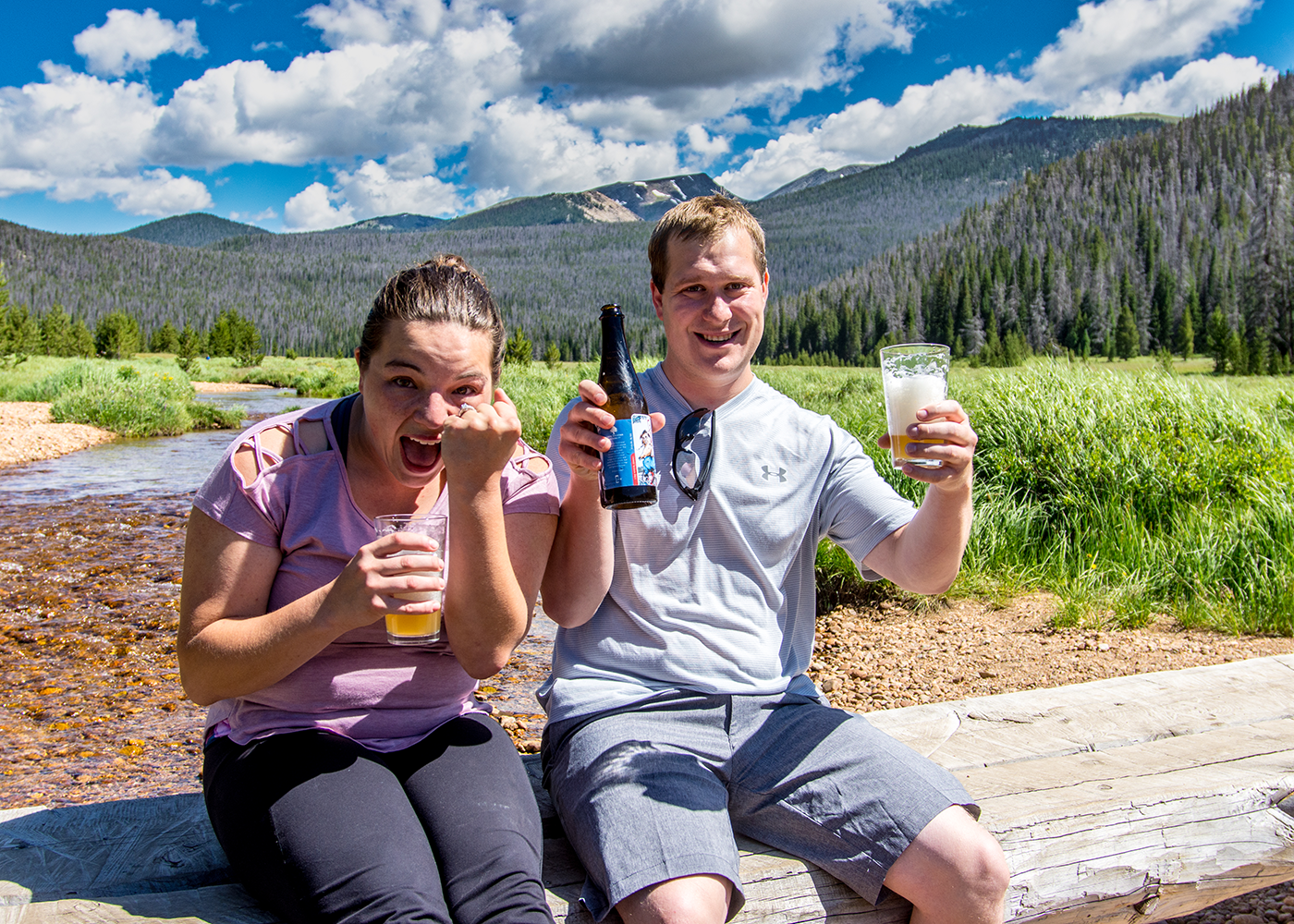 Couple celebrating a successful marriage proposal with beers at Big Meadow in Rocky Mountain National Park in Colorado.