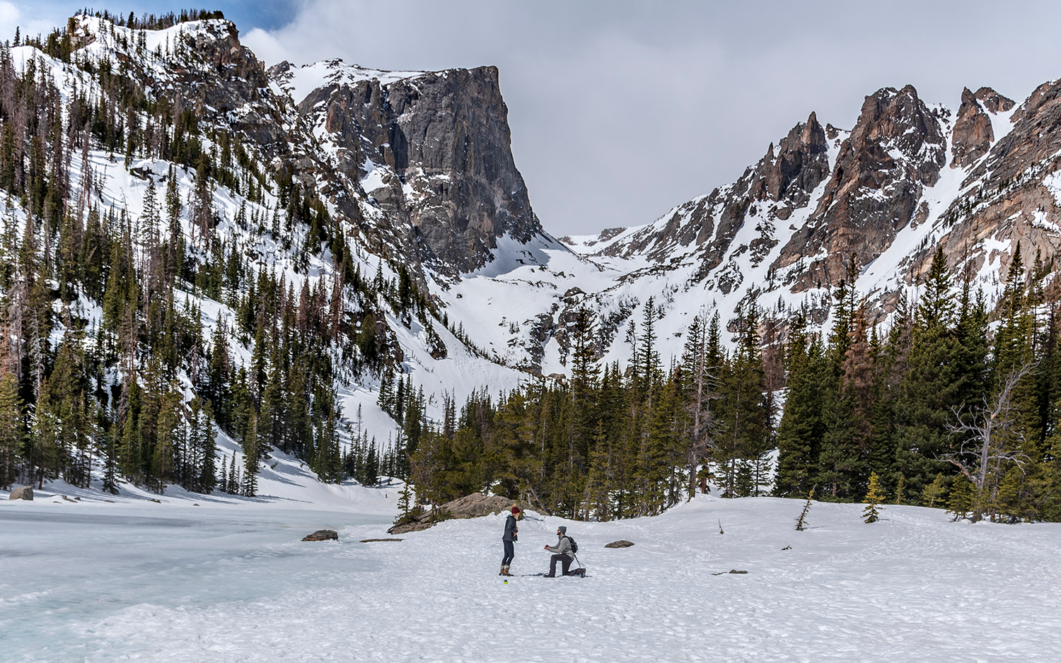 Snow-covered mountain peaks and frozen pond create a stunning winter marriage proposal at Dream Lake in the Rocky Mountain National Park