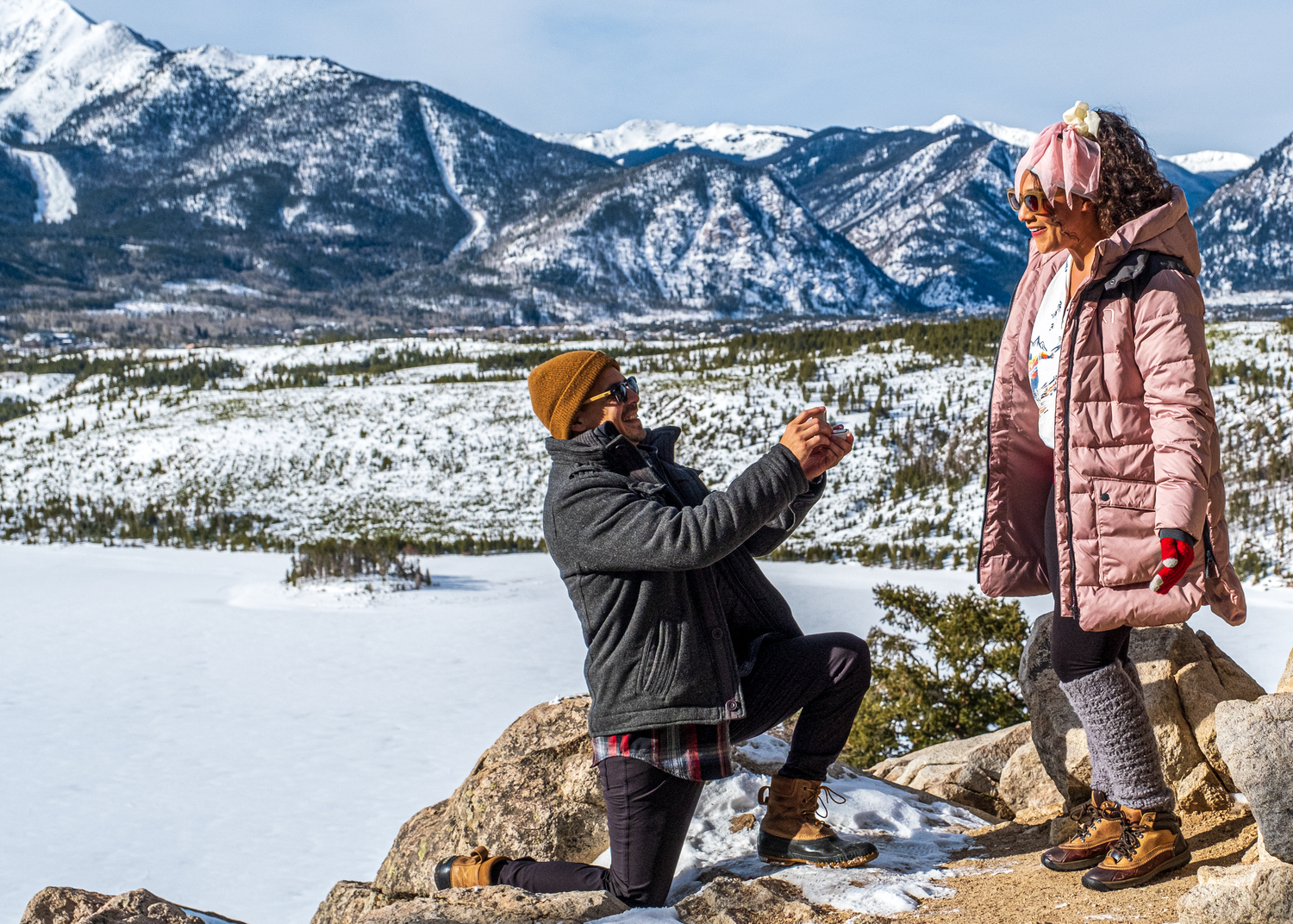 A person proposes on one knee in the snow with snowy mountains and winter landscape at Sapphire Point Overlook in Colorado