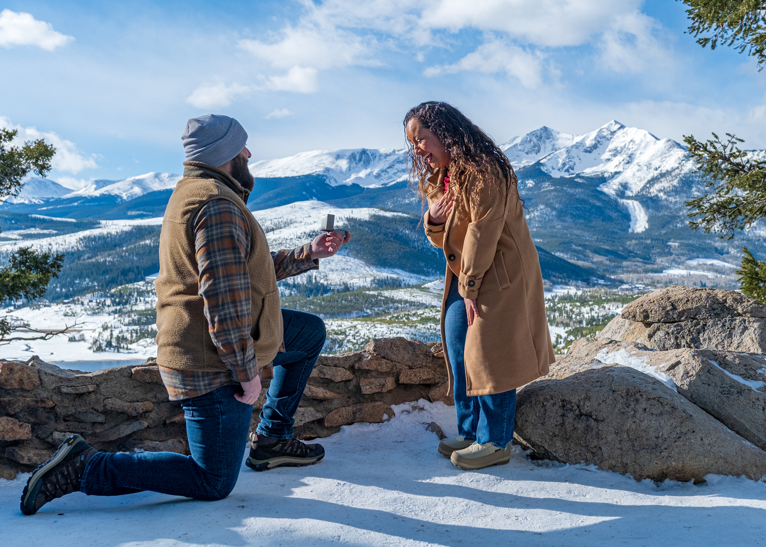 A surprise proposal moment unfolds Sapphire Point Overlook with snow-capped peaks in the background.