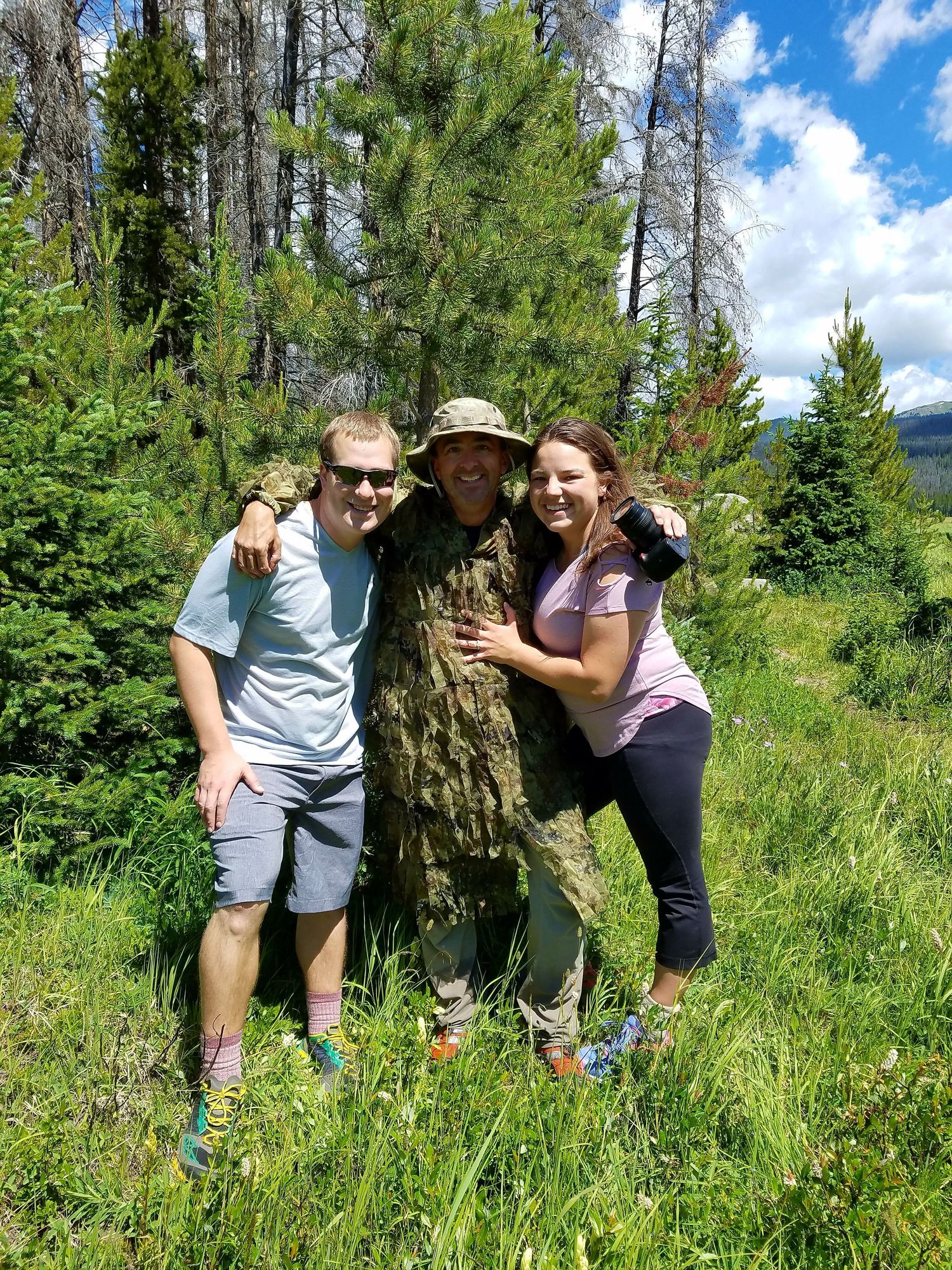 Couple with their hidden photographer in Rocky Mountain National Park after their marriage proposal.