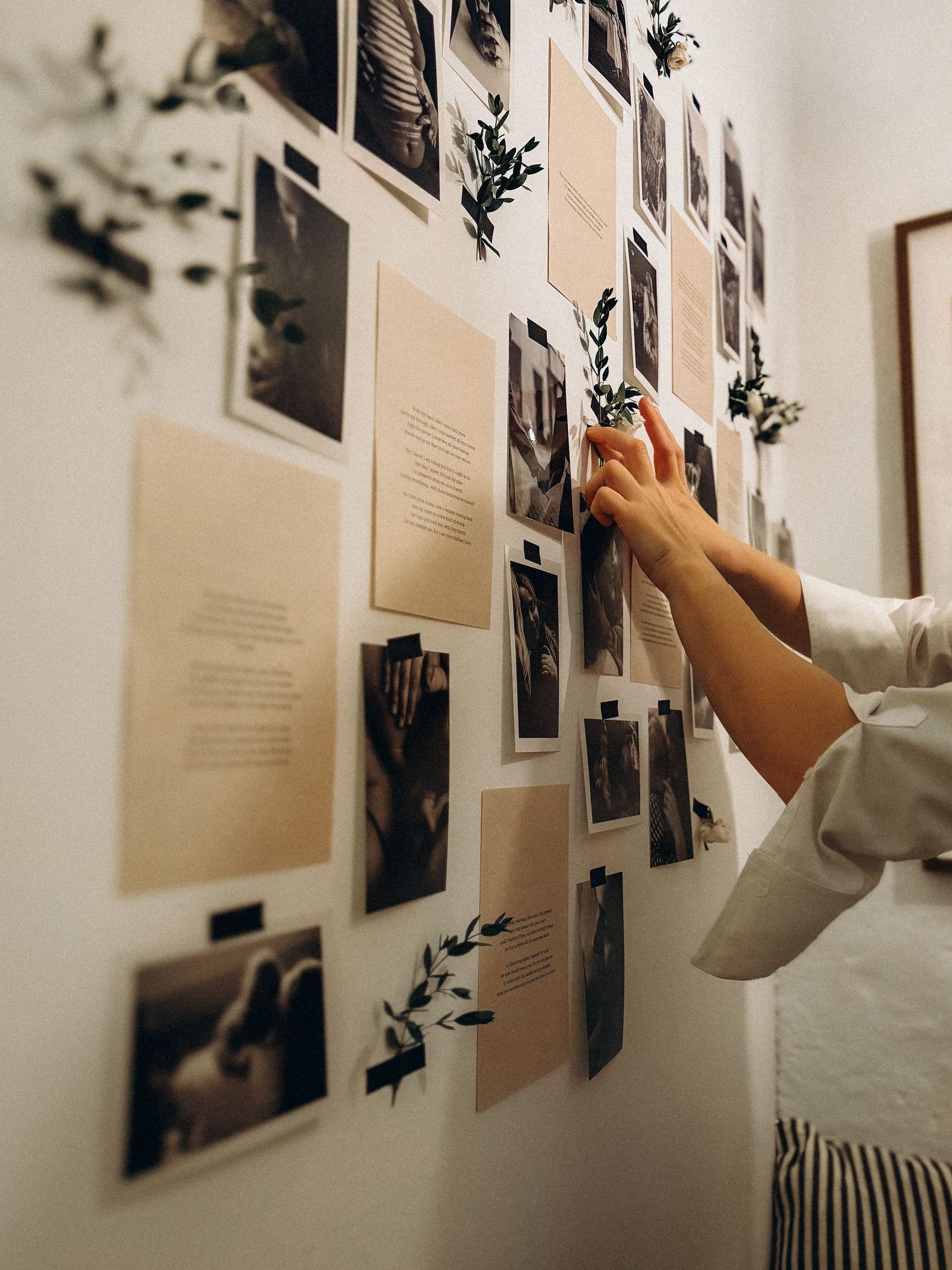 detail of hands attaching a bundle of flowers to a photo wall during exhibition for motherhood photographer in Stockholm