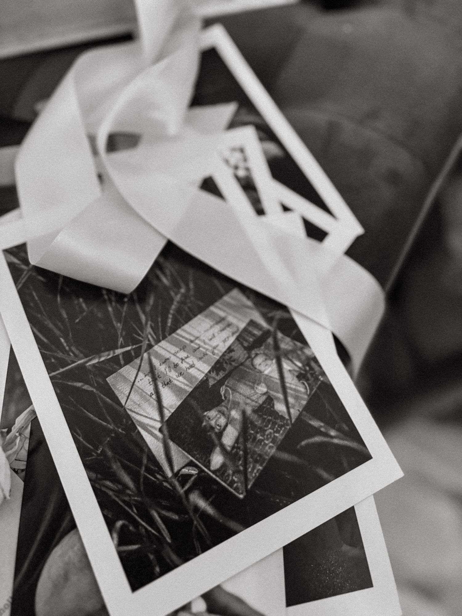 stack of photos on a bench with black and white photo of a mother lying in bed with her baby on top during photography exhibition