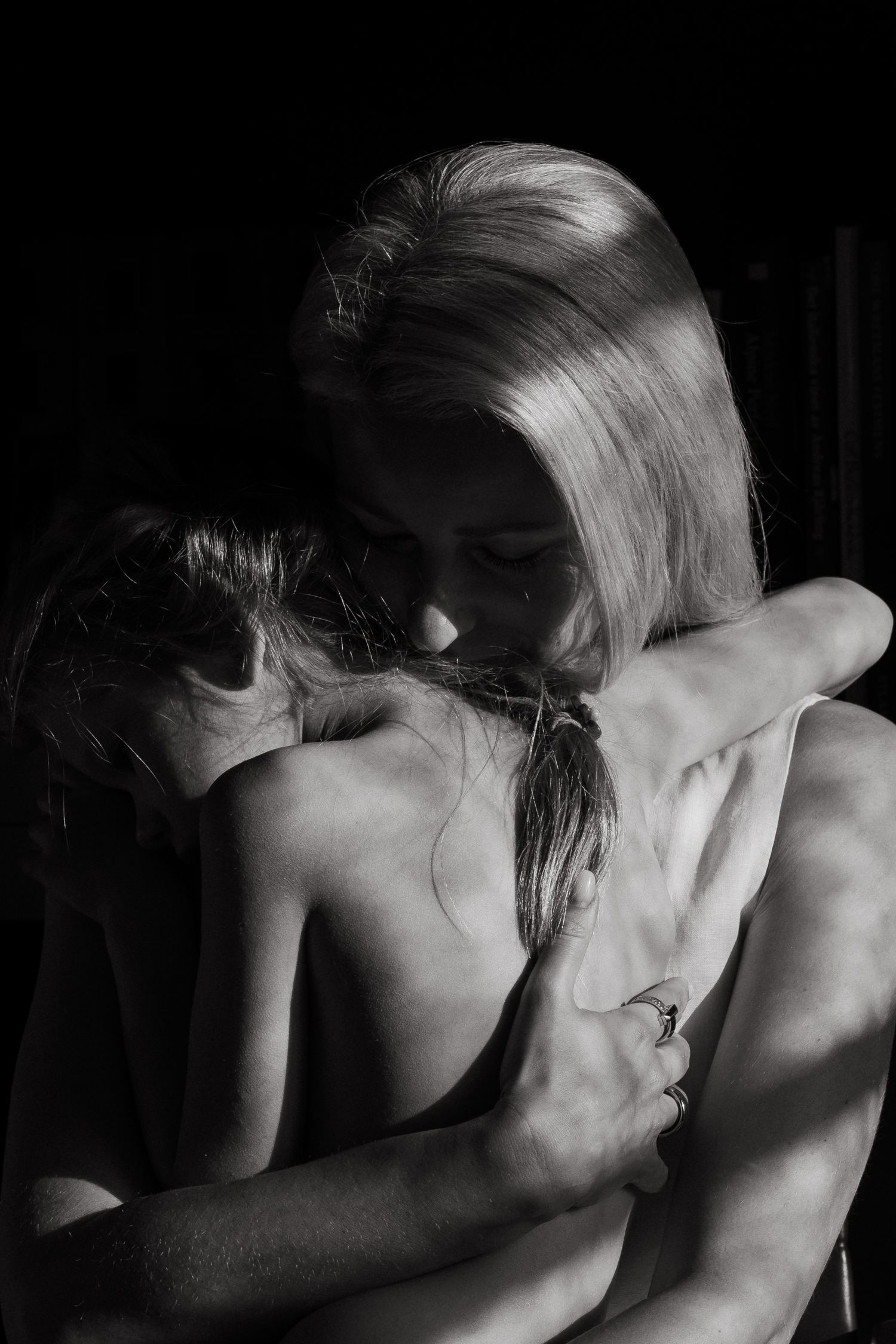 mother hugging her little girl as they're both covered by black shadow during family photoshoot in Stockholm